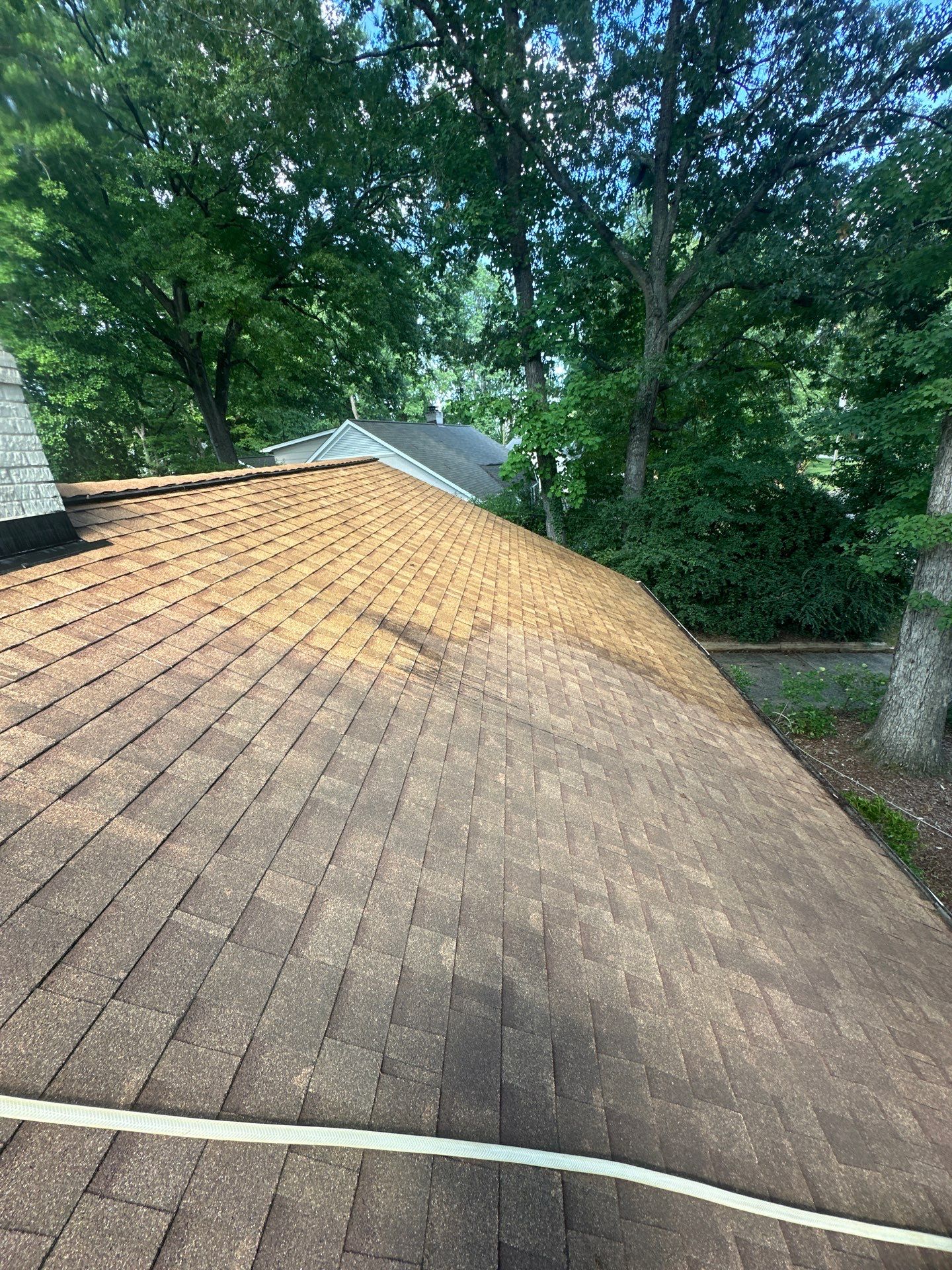 roof cleaning being done on shingled roof with pressure washing equipments