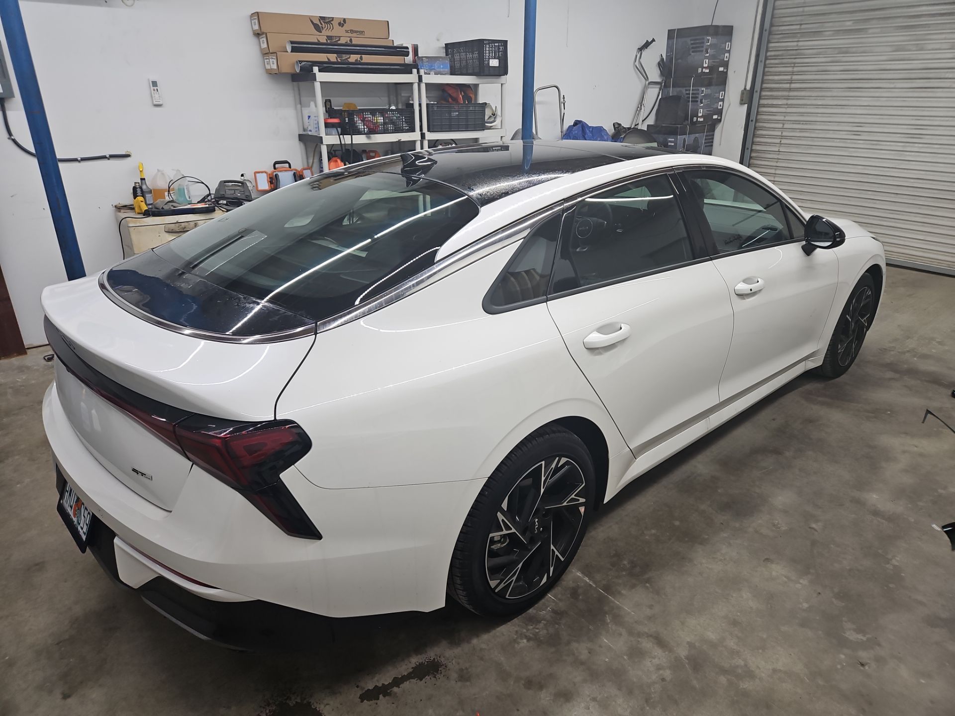 the service being done is the installation of window tint on a white sedan this involves applying a film to the windows to reduce glare and heat while providing privacy the vehicle is likely being prepared for the application which includes cleaning and ensuring the surface is ready for the tint installation the process enhances the car's appearance and offers protection from uv rays and heat