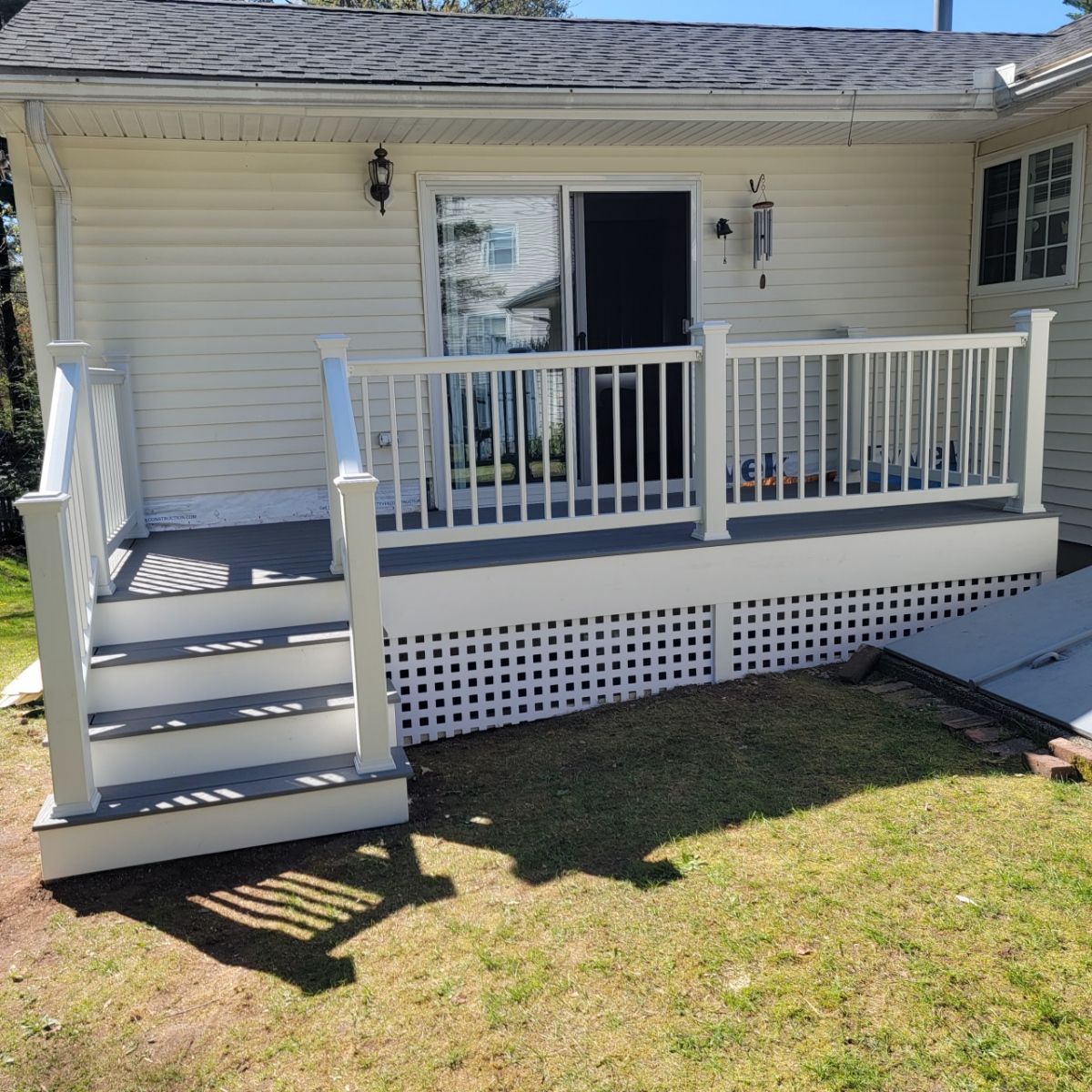 Replacement back deck using Trex Pebble Gray boards, White Composite railings and lattice. by DiGiorgi Roofing and Siding Inc
