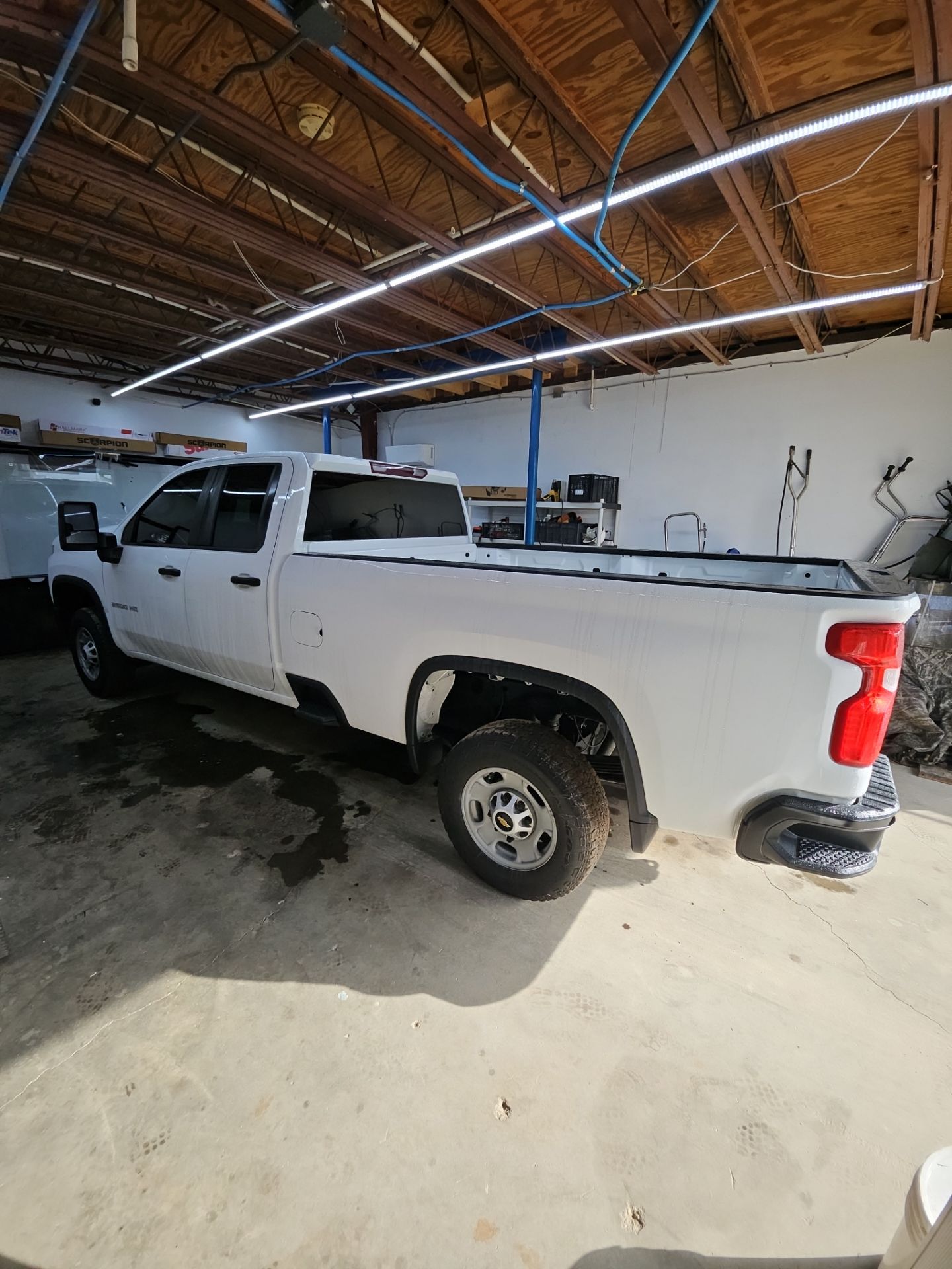 the image shows a white pickup truck inside a garage being prepared for window tinting the vehicle appears to have had its windows cleaned and there may be some masking in place for the tinting process the overall focus is on applying a tint to enhance privacy and reduce heat inside the truck the garage is well lit indicating a professional setting for the service