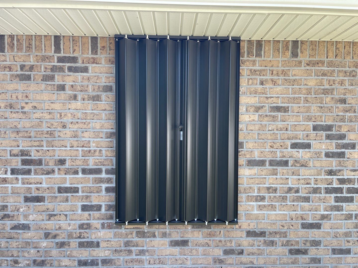 Bronze Accordions on brick home by Smart Guard Shutters