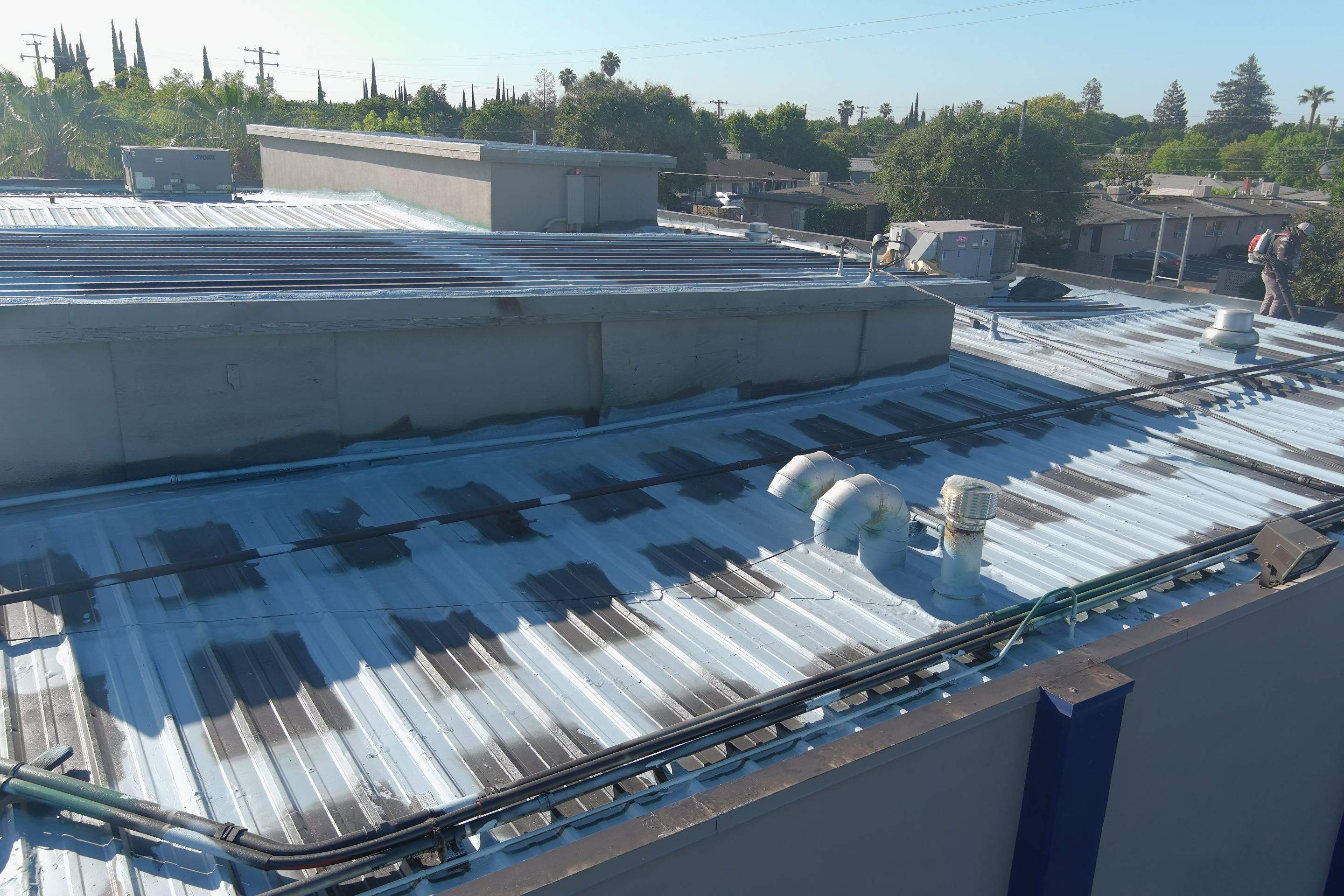 Metal roof restoration on commercial roof using Conklin Benchmark/ PUMA XL acrylic coatings over metal and foam by Straight Edge Roofing Inc