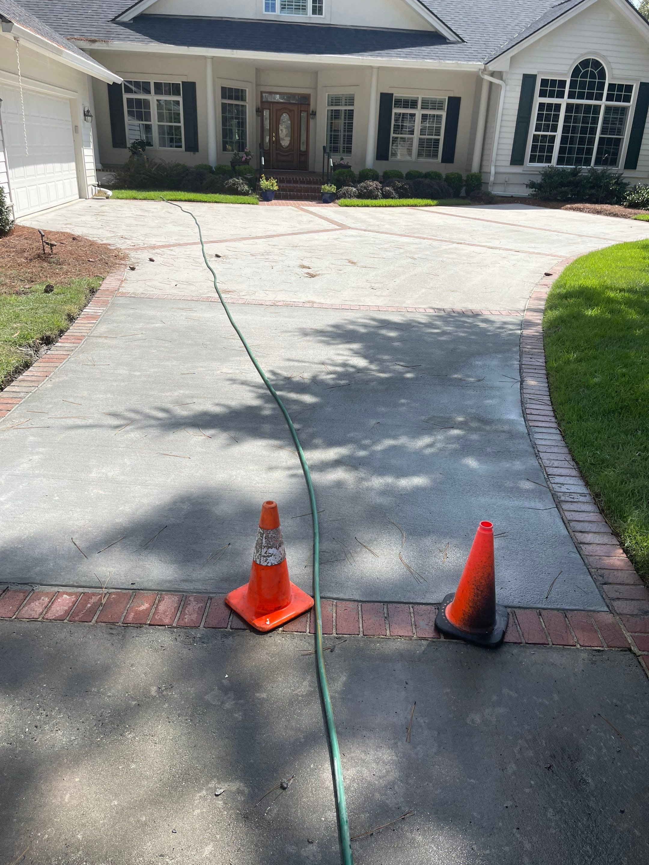 Concrete Driveway Cleaning and Restoration With Decorative Red Brick Border by Lowcountry Scapes, LLC