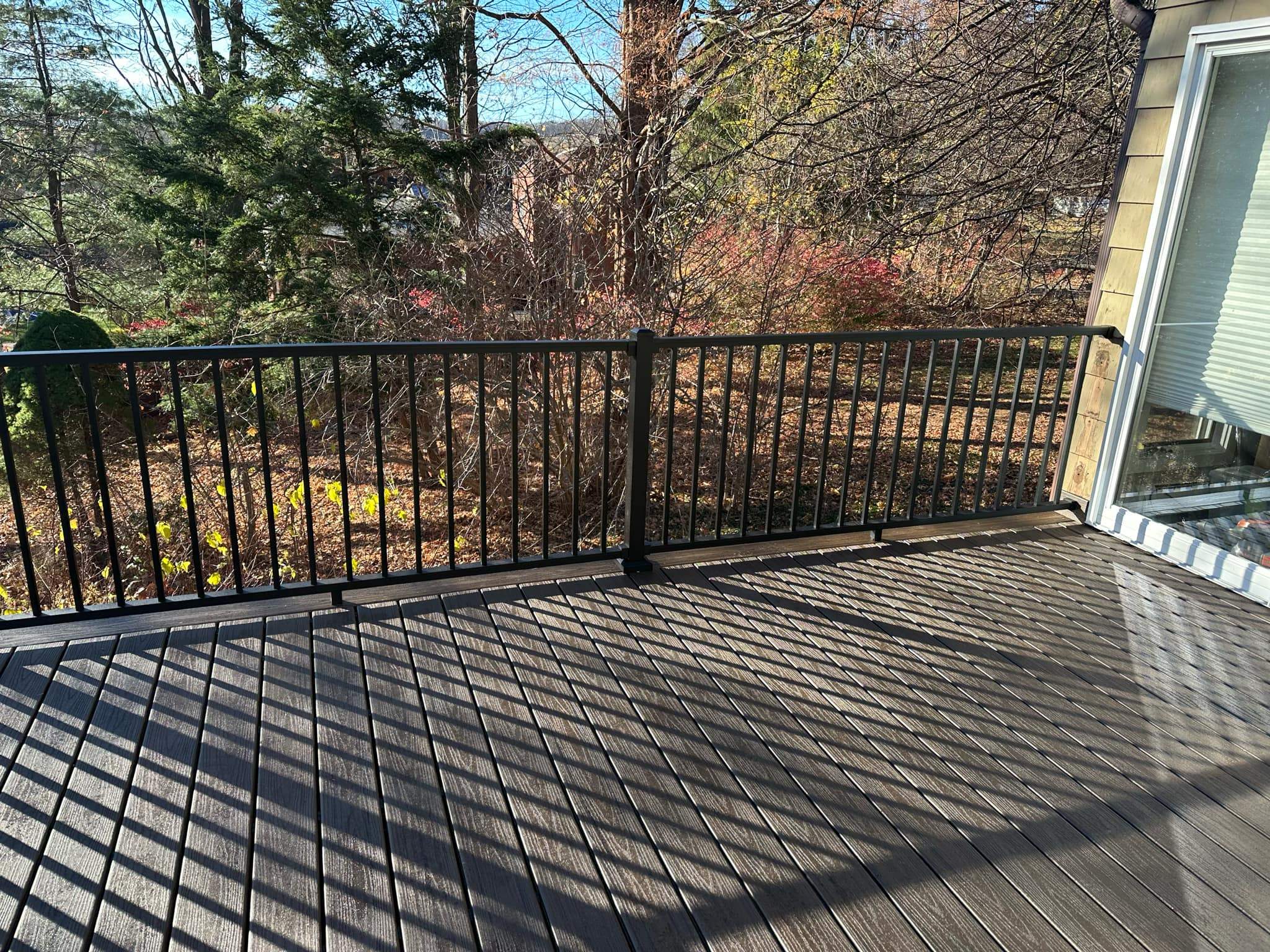 Replacement deck on top of flat roof, Trex Tropical Spiced rum boards and fascia, Trex signature aluminum railings in Black. by DiGiorgi Roofing and Siding Inc