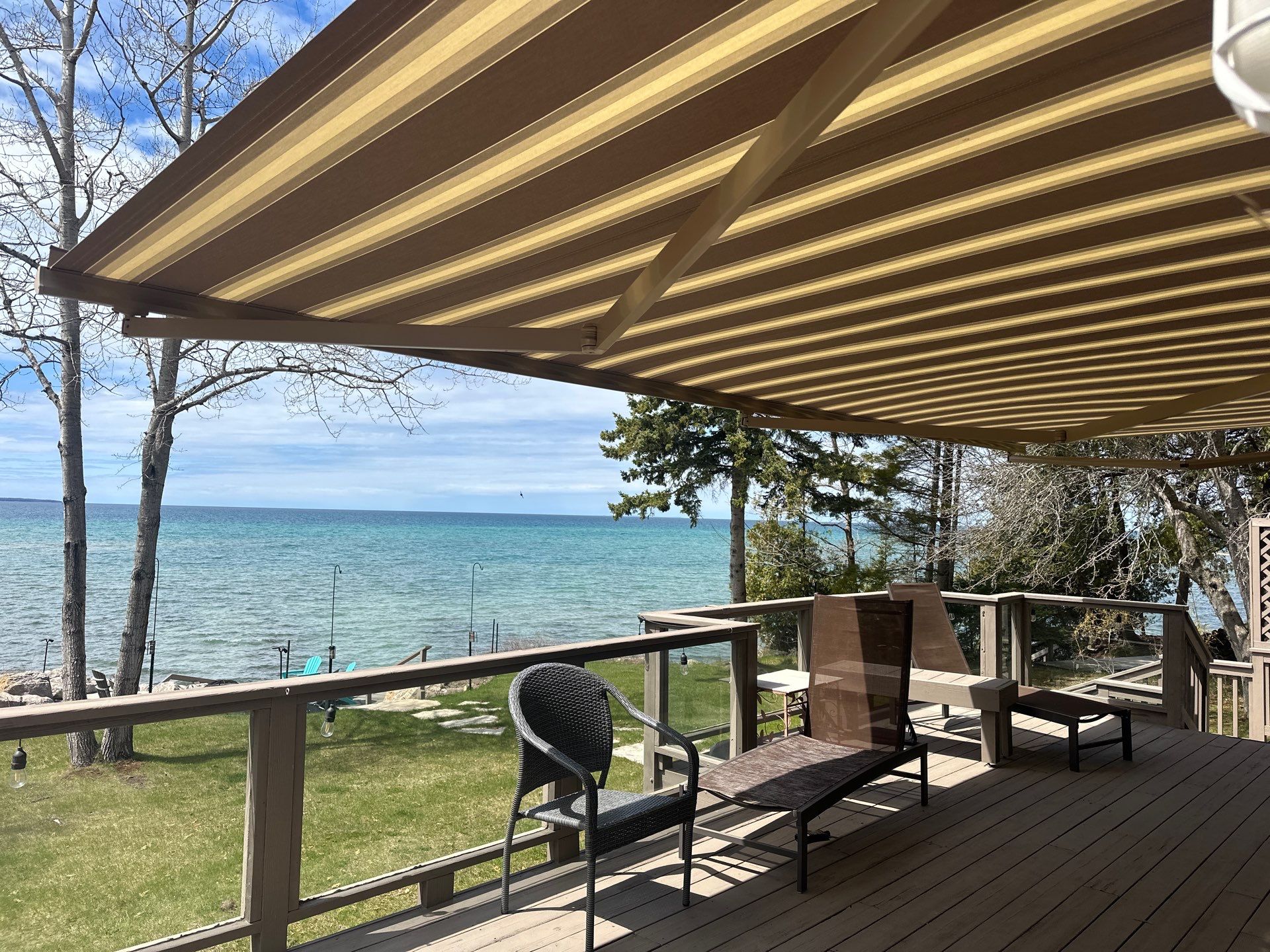 Retractable Striped Awning Installation for Waterfront Composite Deck in Charlevoix by Rainbow Seamless Systems