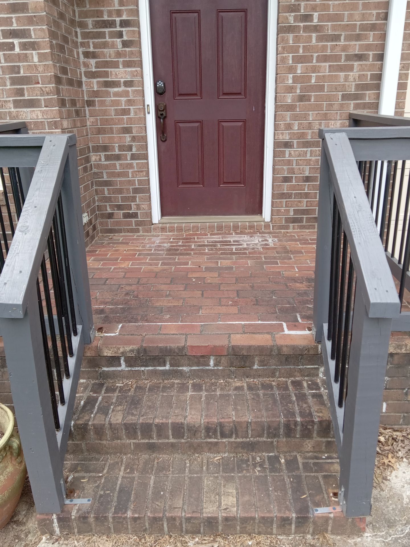 the pressure washing company is cleaning the brick steps leading up to the front door the steps show a clear difference where the pressure washing has cleaned the bricks making them look much newer compared to the untreated section which looks dirtier this service helps to refresh the entryway by removing built-up grime and restoring the appearance of the bricks