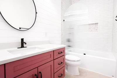 Stone Oak Hall Bathroom Remodel with Pink Vanity and Curved Shower Glass