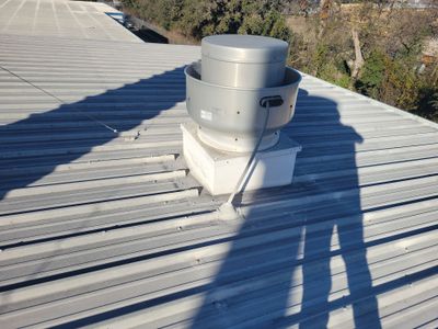 Metal roof with a mechanical ventilation fan unit.