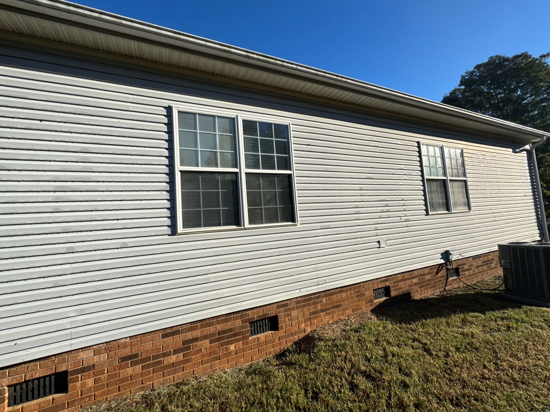 the service being done is cleaning the exterior siding and brick foundation of a house using pressure washing techniques