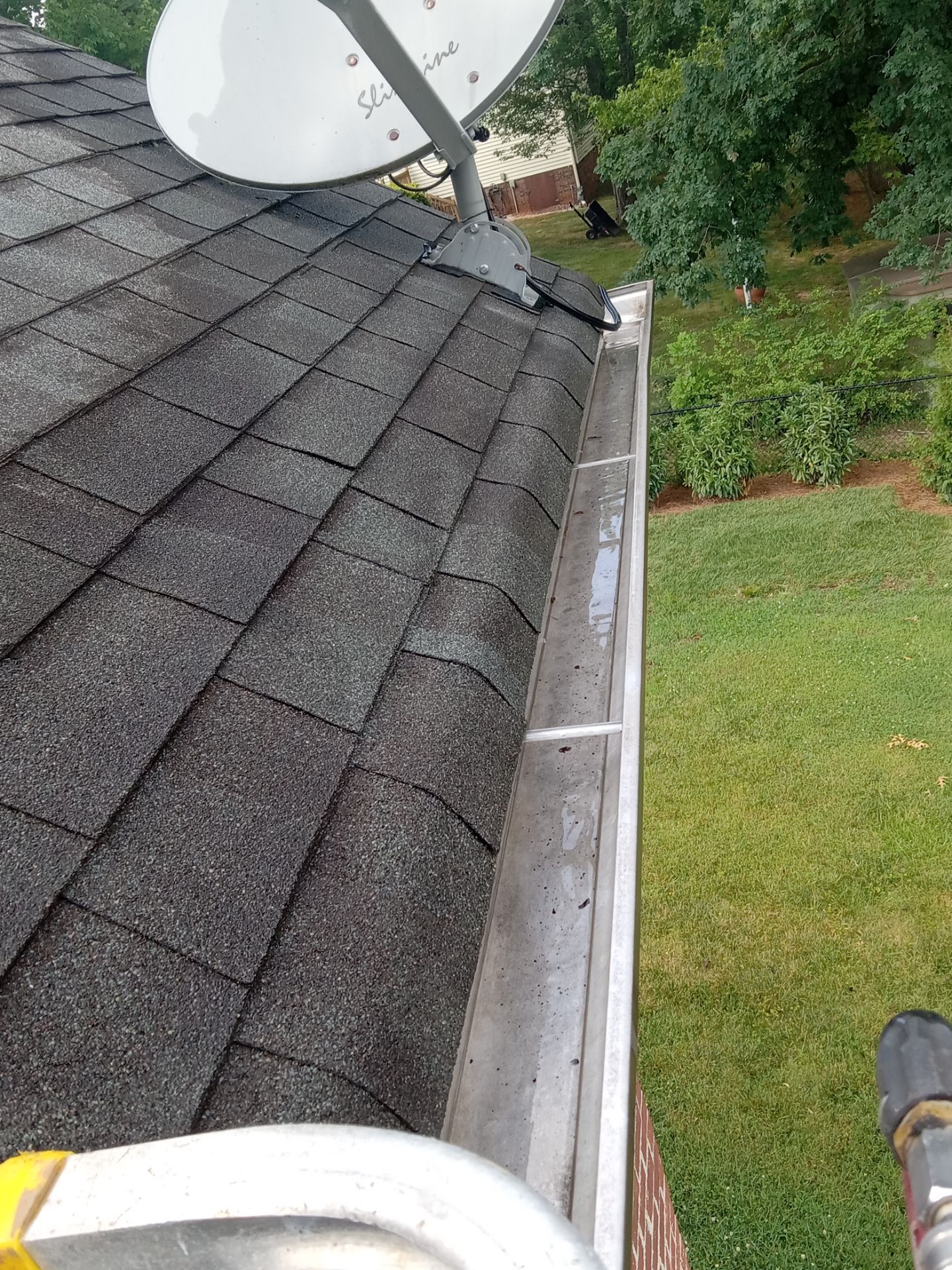 pressure washing service cleaning a residential roof and gutter removing dirt debris and stains for home maintenance