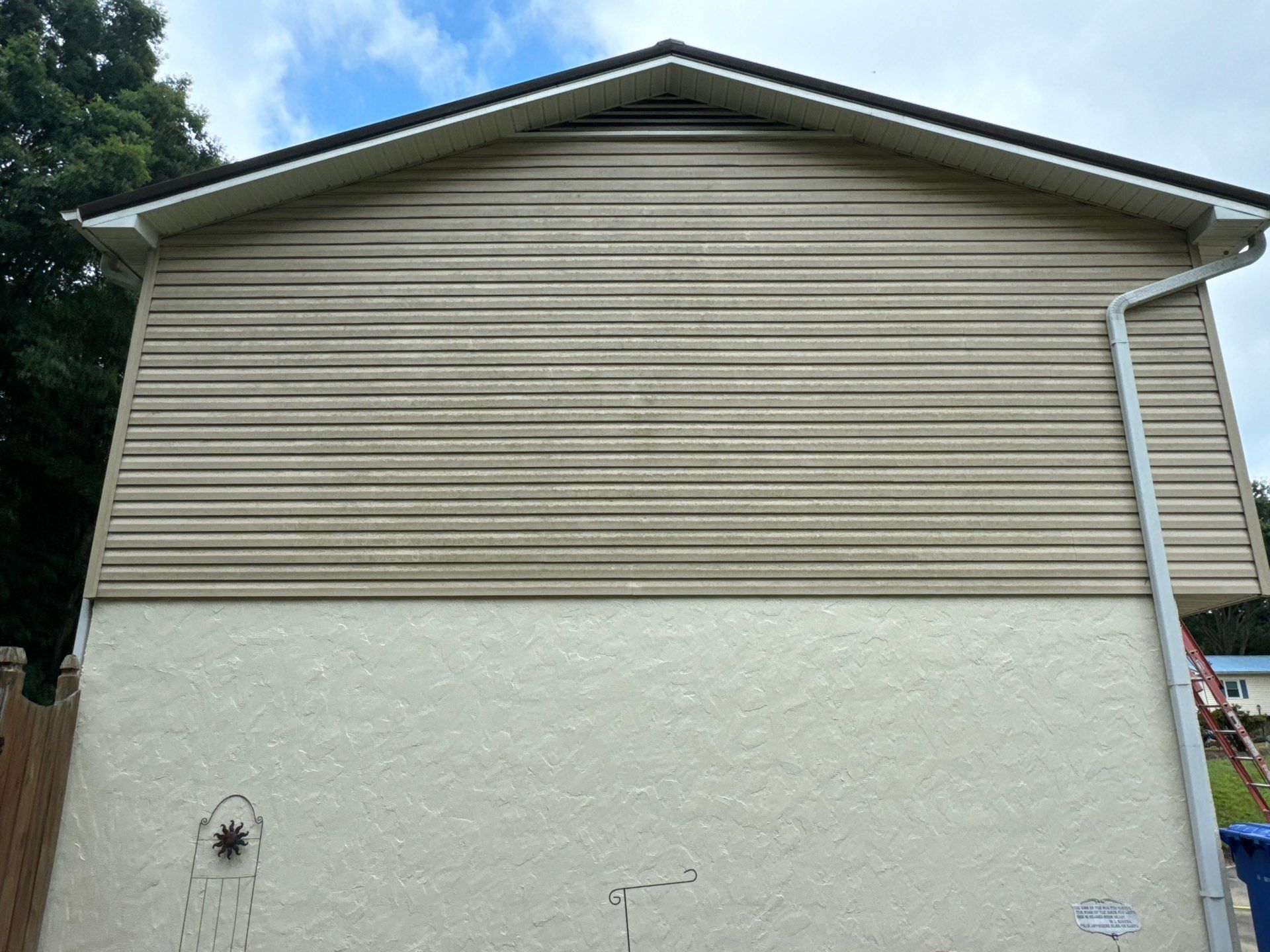 house washing on the side of a house with vinyl siding and stucco surfaces