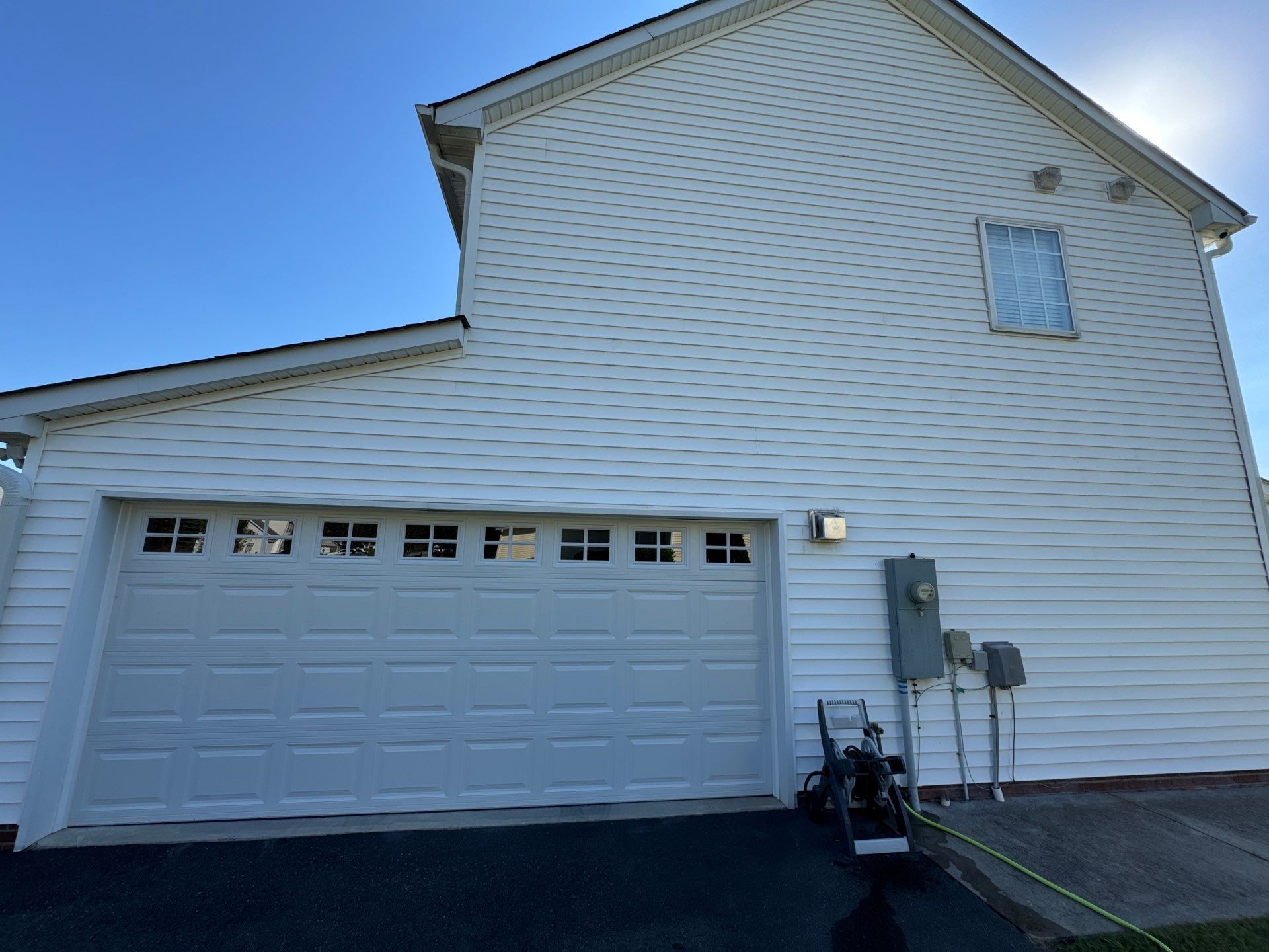 the service being done is cleaning the vinyl siding and garage door of a house using pressure washing techniques