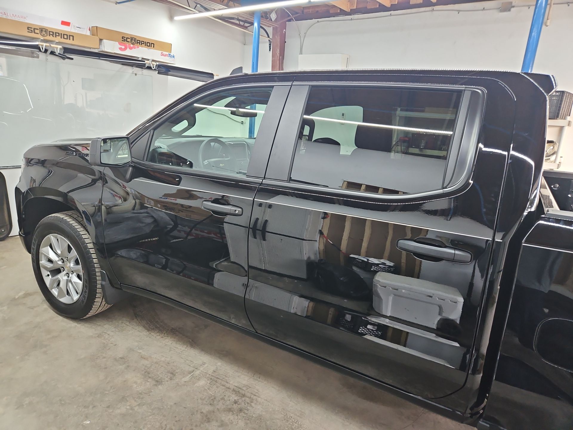 the image shows a black pickup truck with window tinting service being performed by t's window tinting the windows appear to be prepped for tint application the interior and exterior reflections indicate a clean area the tint will provide privacy and reduce heat inside the vehicle the professional setting suggests attention to detail ensuring a quality finish the overall appearance of the truck enhances with the tint being applied