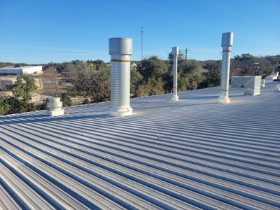 Metal roof with ventilation pipes and surrounding trees
