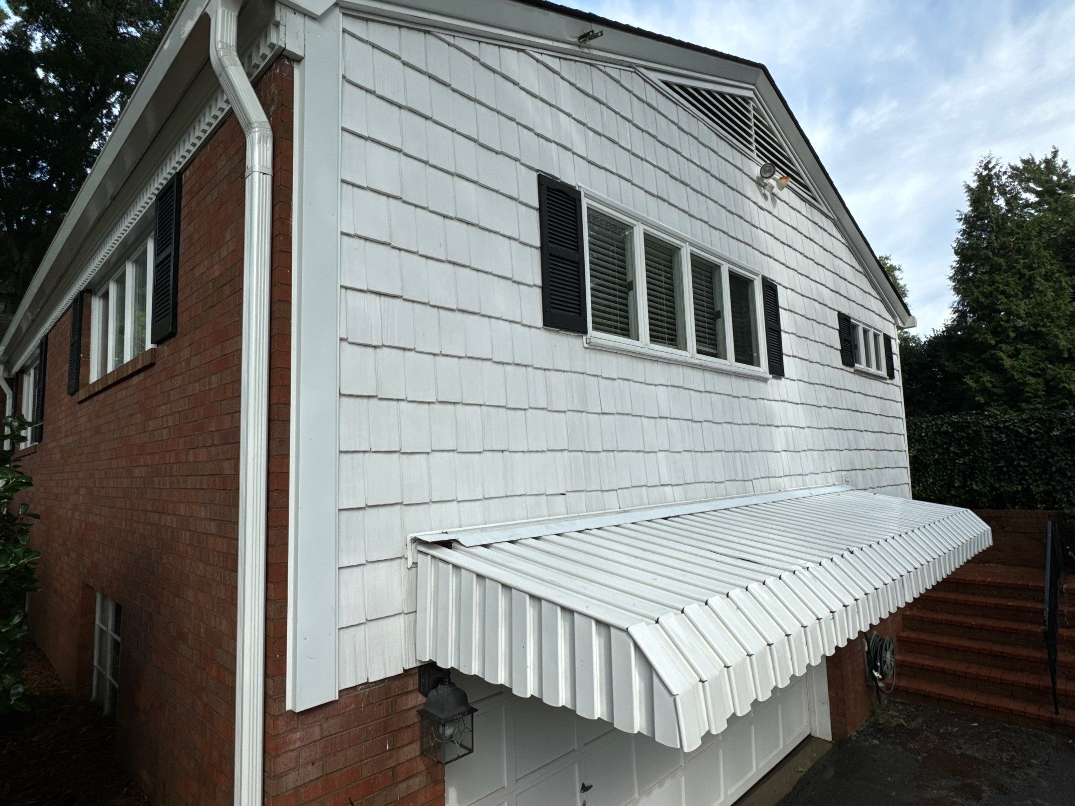 the service is cleaning the exterior of a house including the brick and siding surfaces with pressure washing techniques