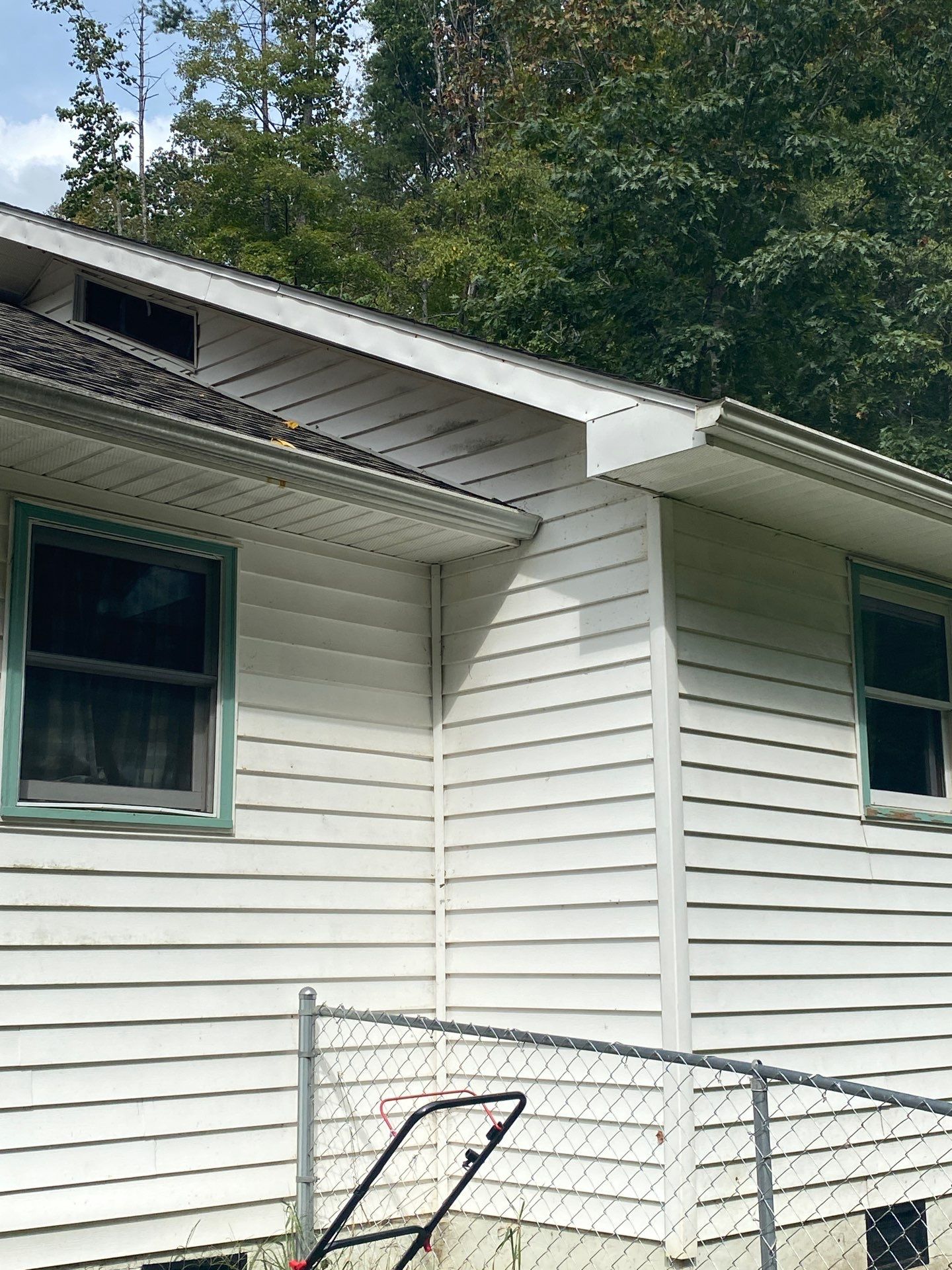 cleaning the exterior siding and gutters of the house using pressure washing techniques to remove dirt and grime