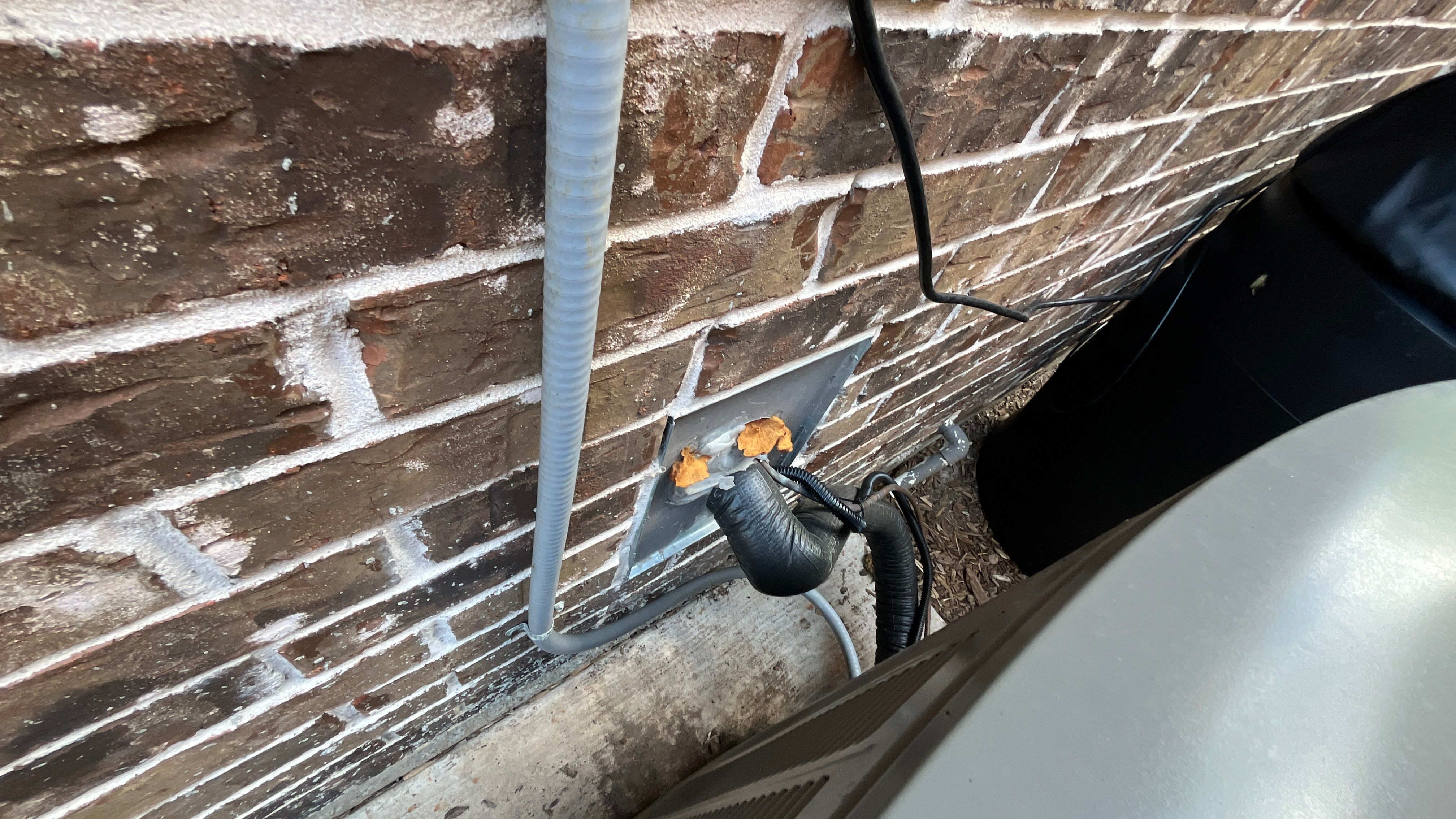 Pest Me Off technician sealing a pipe gap in the brick on a McKinney TX home