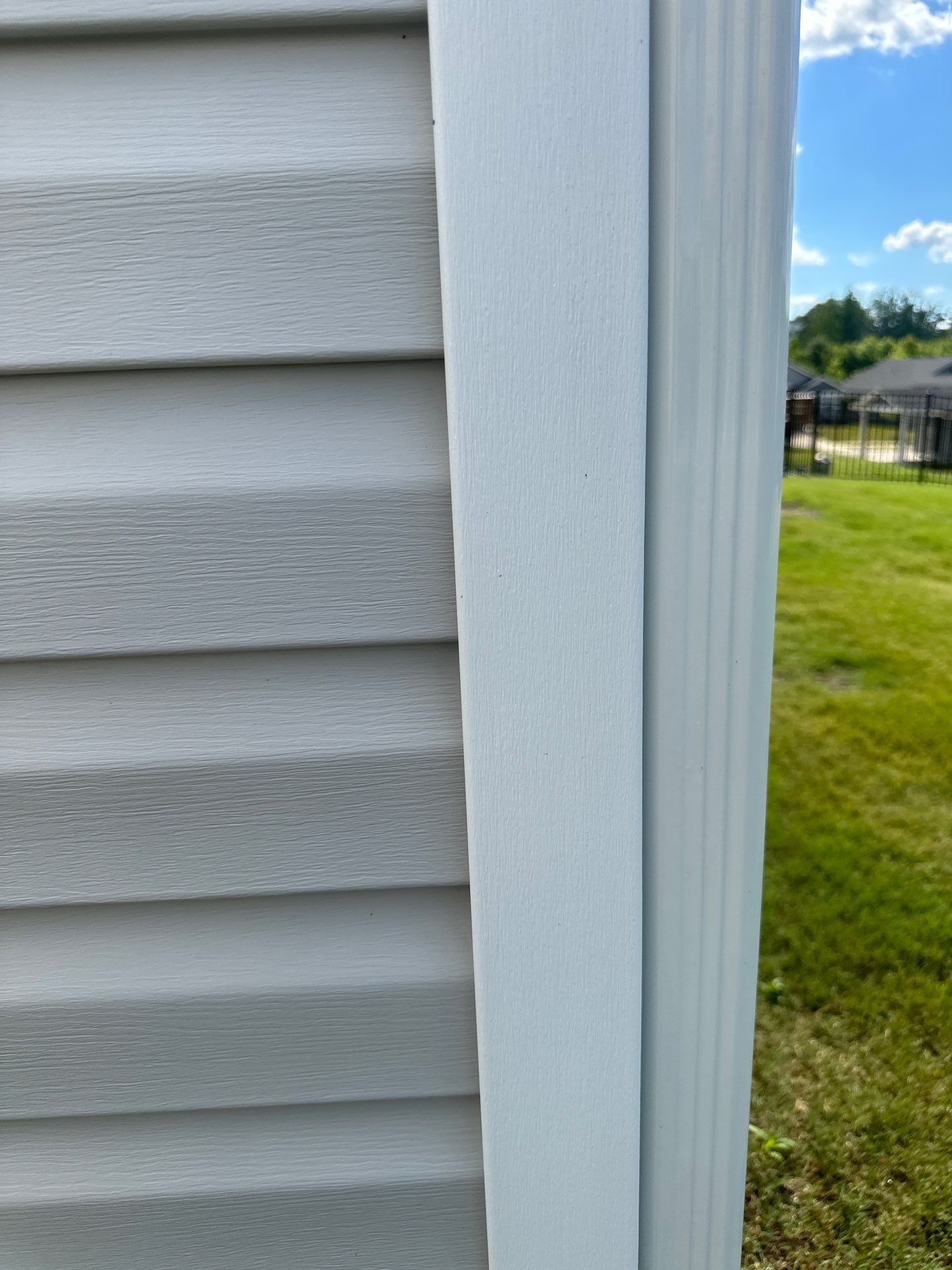 the pressure washing company is cleaning the exterior siding and trim of a residential building the vinyl siding shows a clear difference between the cleaned and the dirty area indicating the effectiveness of the pressure washing technique the trim appears to be a contrast against the siding symbolizing a neat and clean appearance after the service this demonstrates a typical exterior house cleaning service offered by pressure washing companies to maintain and enhance the look of a home