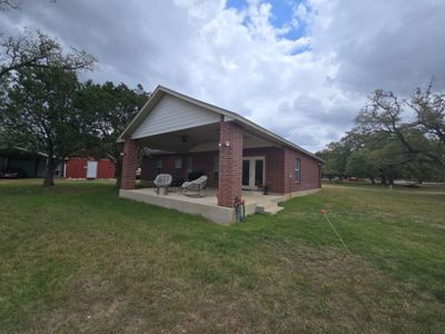 Completed asphalt shingle roof on brick home with patio