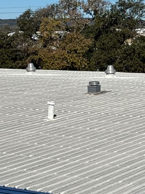 Metal roof with multiple vents and clear blue sky