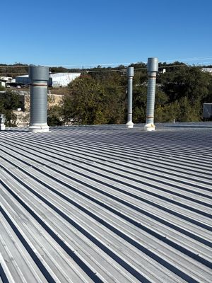 Metal roof with multiple vent pipes and clear sky