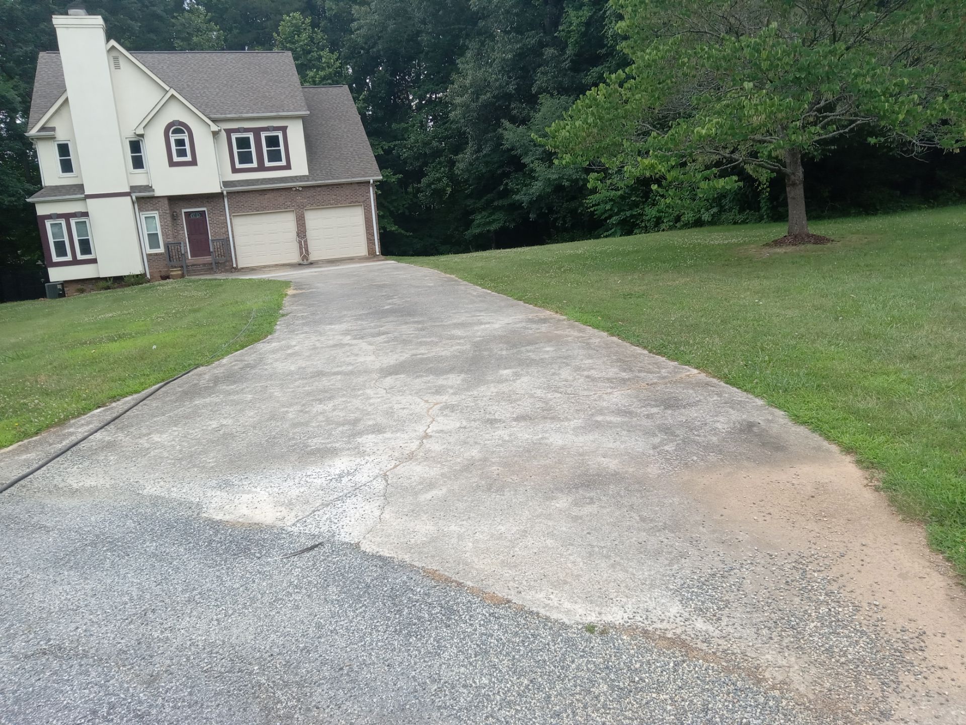 the pressure washing company is likely cleaning the driveway of a residential home you can see the contrast where the surface has been cleaned compared to the still dirty part indicating the effectiveness of the pressure washing the cleaner surface appears lighter due to the removal of dirt grime and possibly mildew or algae this service typically restores the look of the driveway by removing accumulated outdoor elements that can make surfaces look aged and dull