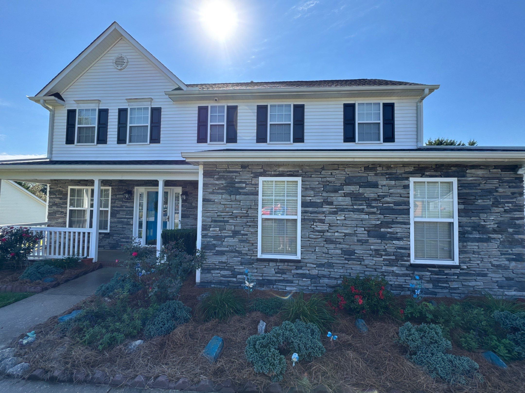 the service is cleaning the exterior siding and stone facade of the house to enhance its appearance and remove dirt