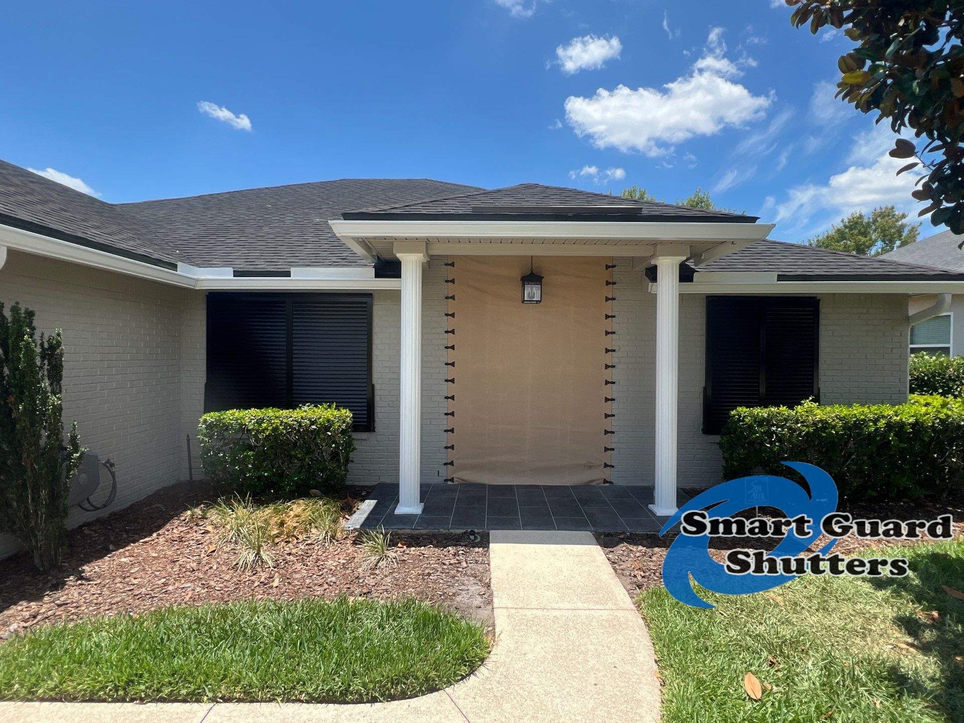 Hurricane Protection using Bahamas in Traffic Black and Fabric in Tan by Smart Guard Shutters