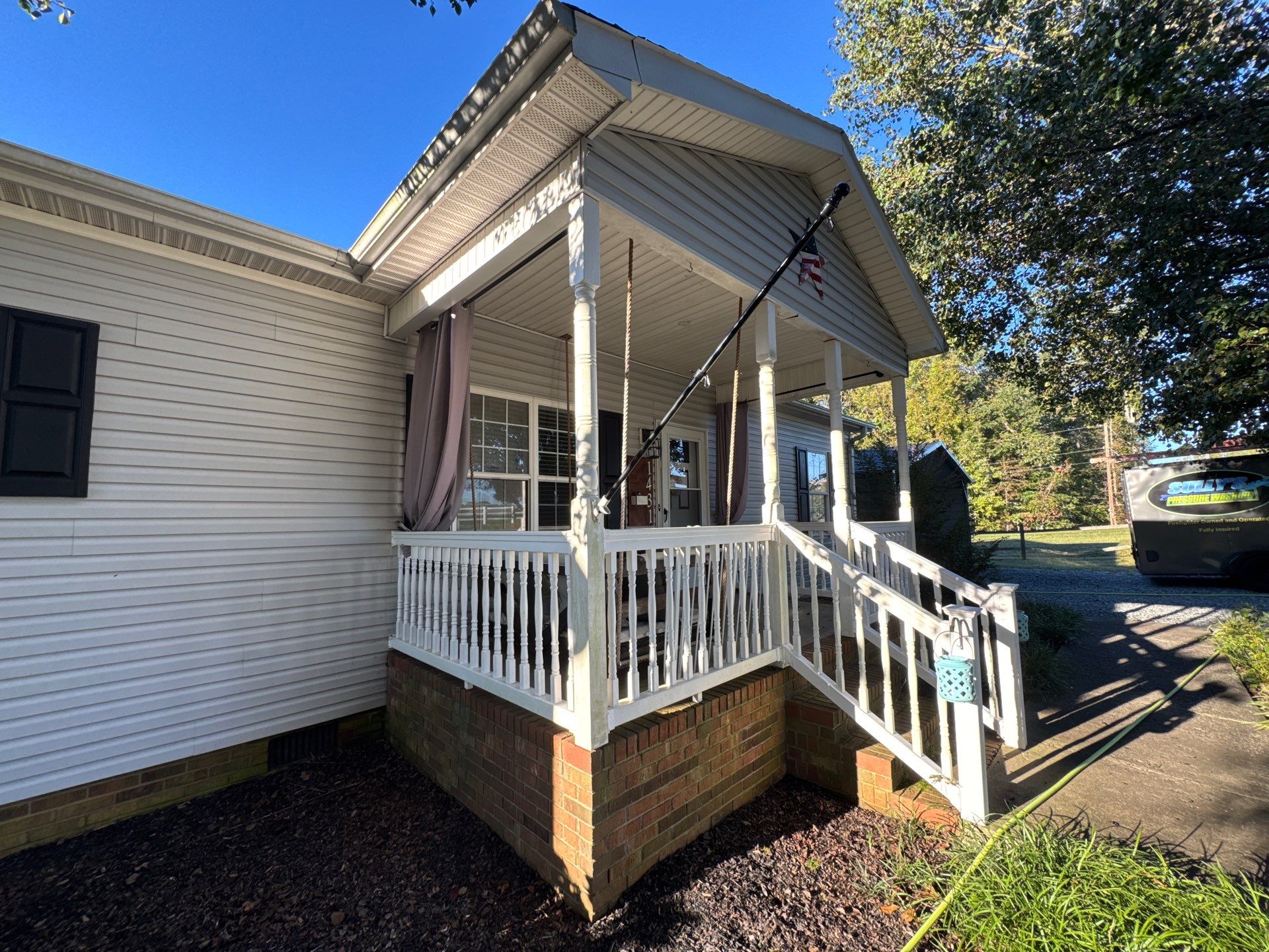 the service shown is cleaning of the house exterior including the porch and surrounding surfaces with a pressure washer