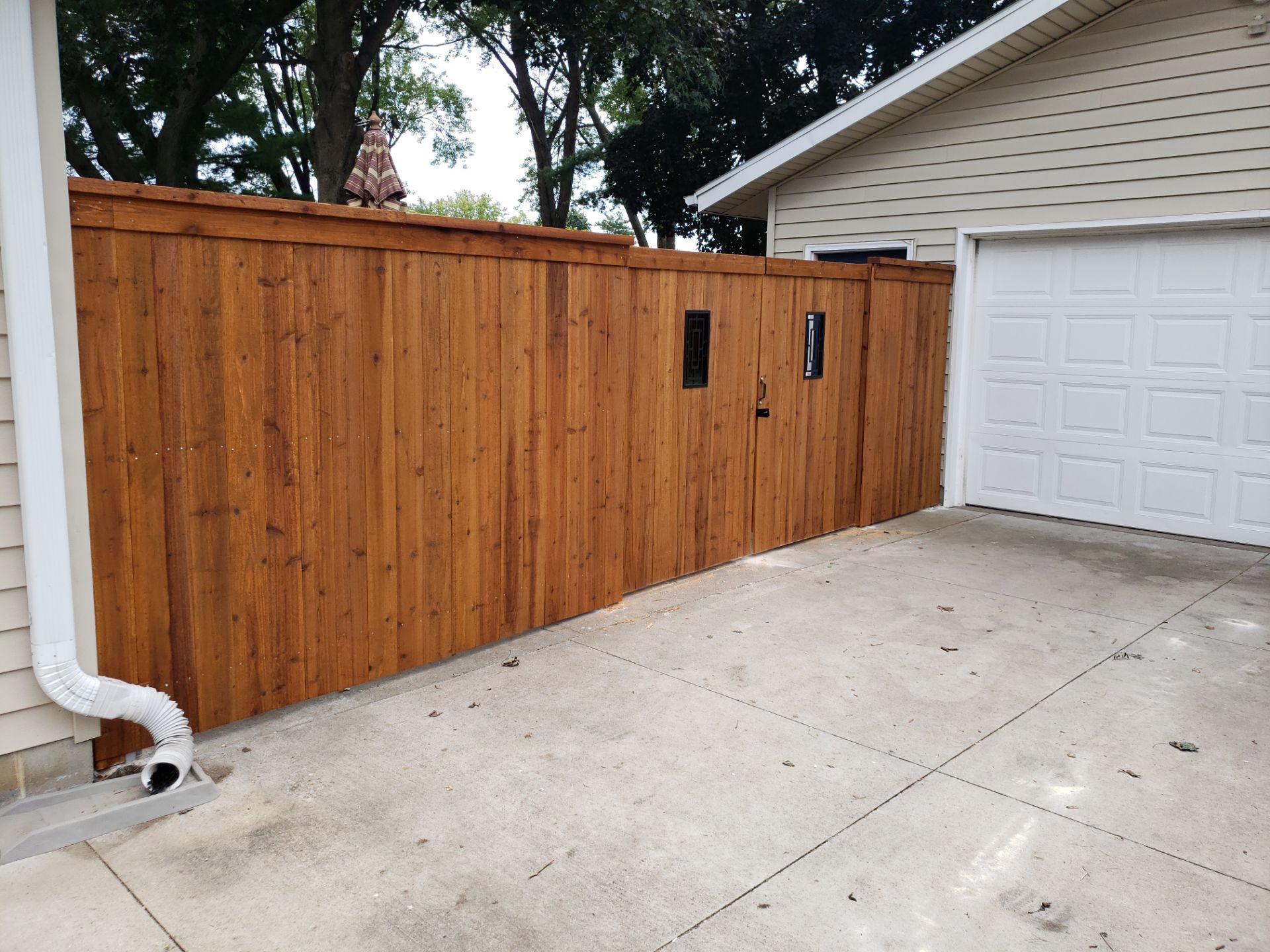 Custom Cedar Privacy Fence with Decorative Gate Windows in Cedar Falls by Perfect Picket Fence and Stain