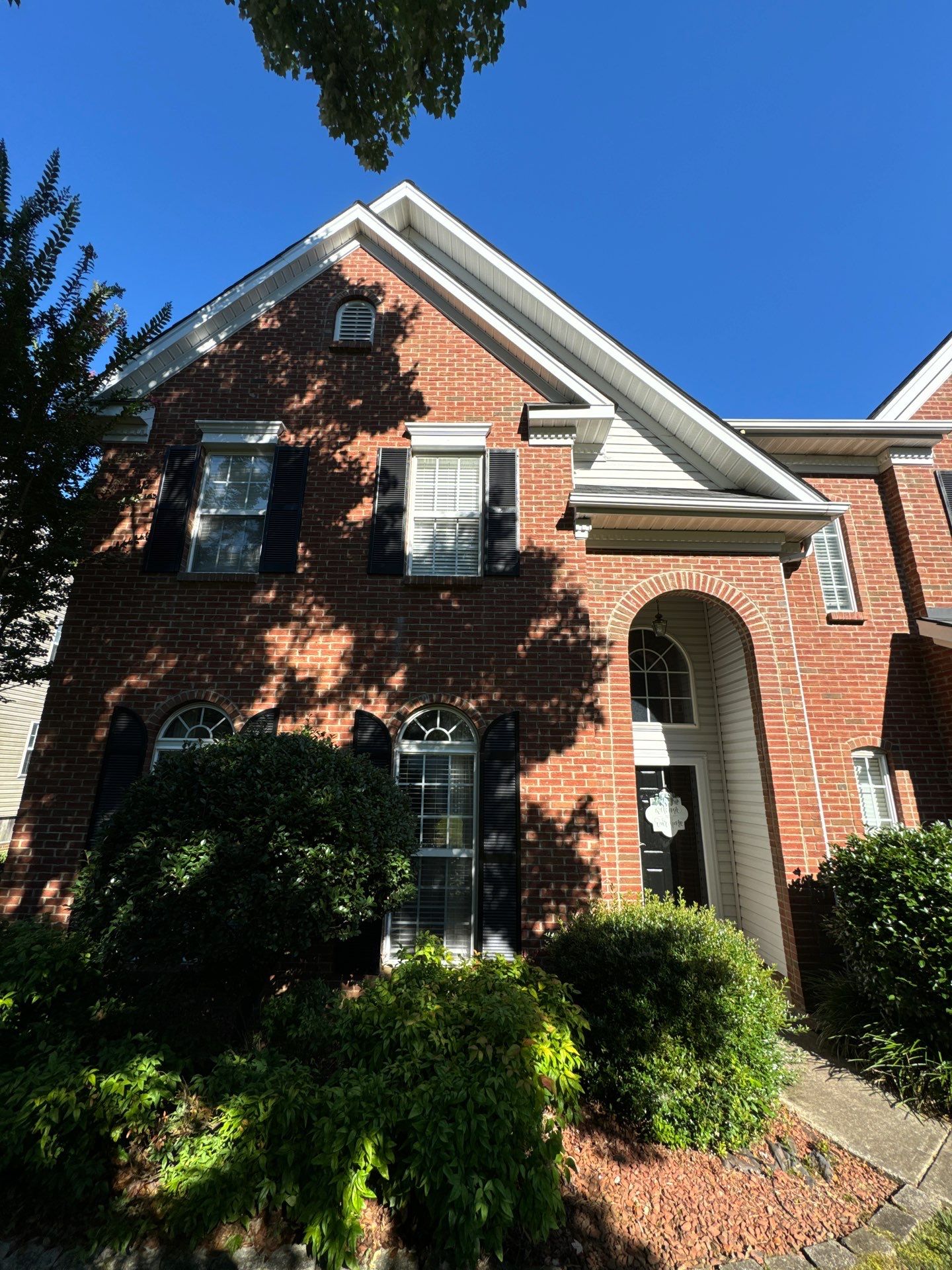 pressure washing company is cleaning the brick siding windows and shutters of this house in winston salem nc