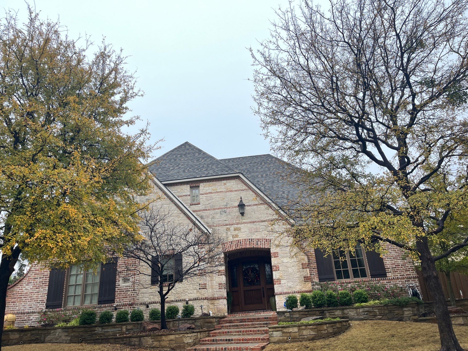 Light red brick/cream stone/espresso shutters with IKO Cornerstone by Tejas Roofworks + Restoration