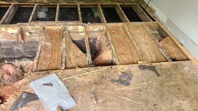 Interior flooring removed to expose wood framing, insulation, and subfloor materials.