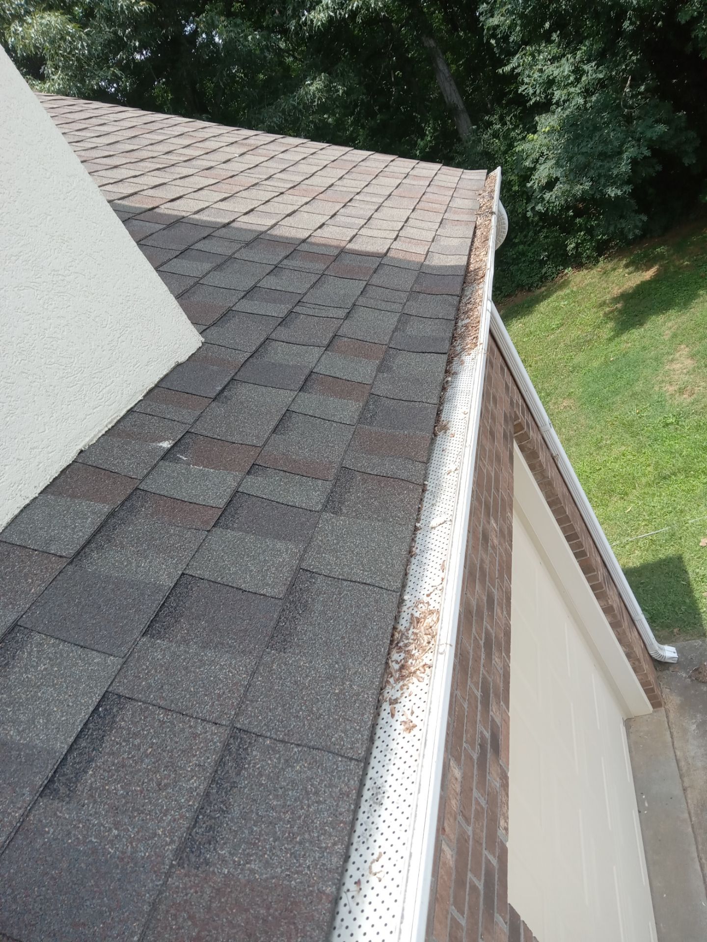 the service being shown in the image seems to be gutter cleaning as part of pressure washing services the presence of leaves and debris in the gutter suggests a need for clearing the gutters to ensure proper water flow from the roof during rainstorms the cleaned gutters will prevent water damage and maintain the home's exterior cleanliness and function