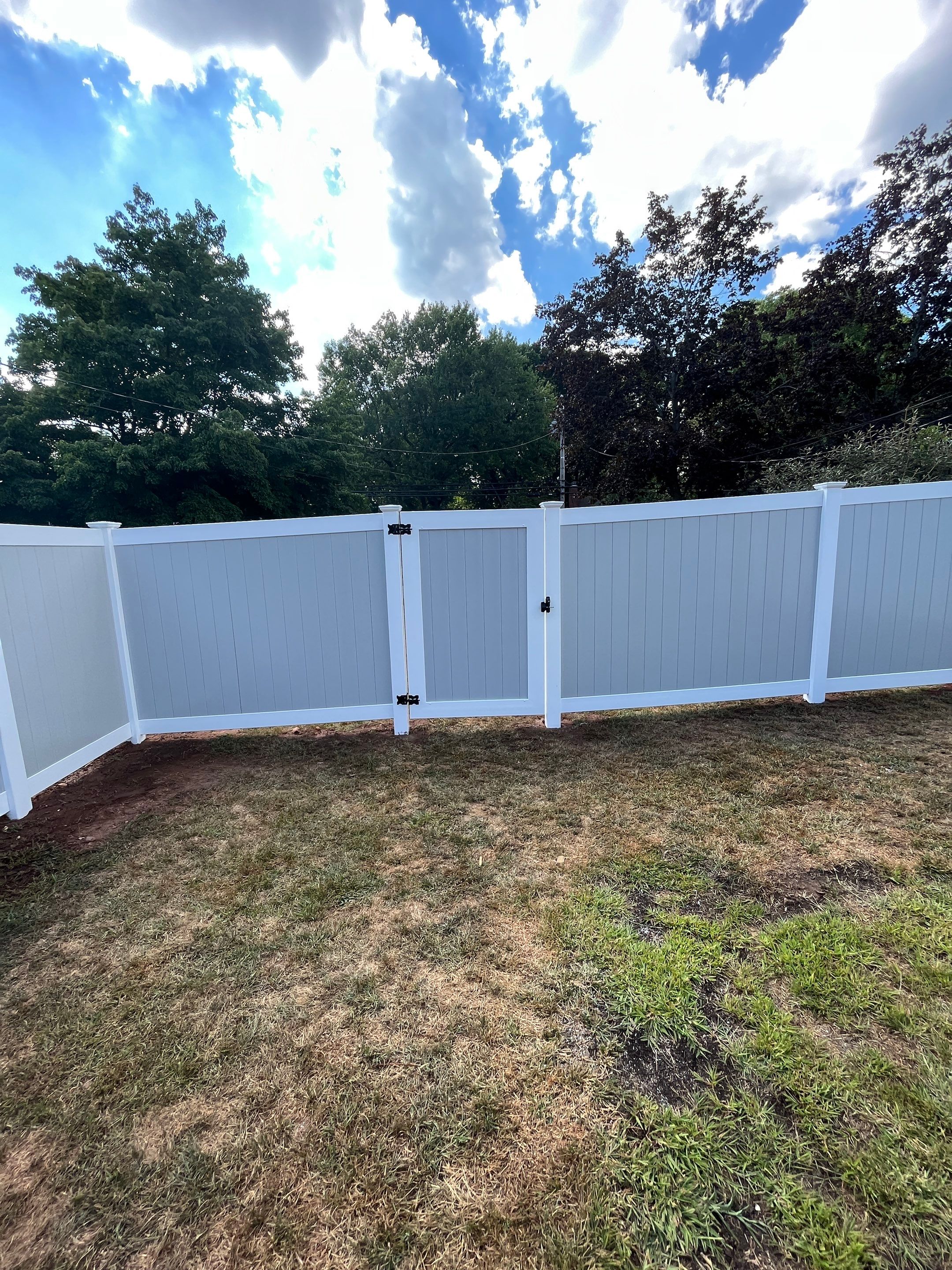 New Vinyl privacy fence with double gate. In two tone gray and white coloring. by DiGiorgi Roofing and Siding Inc