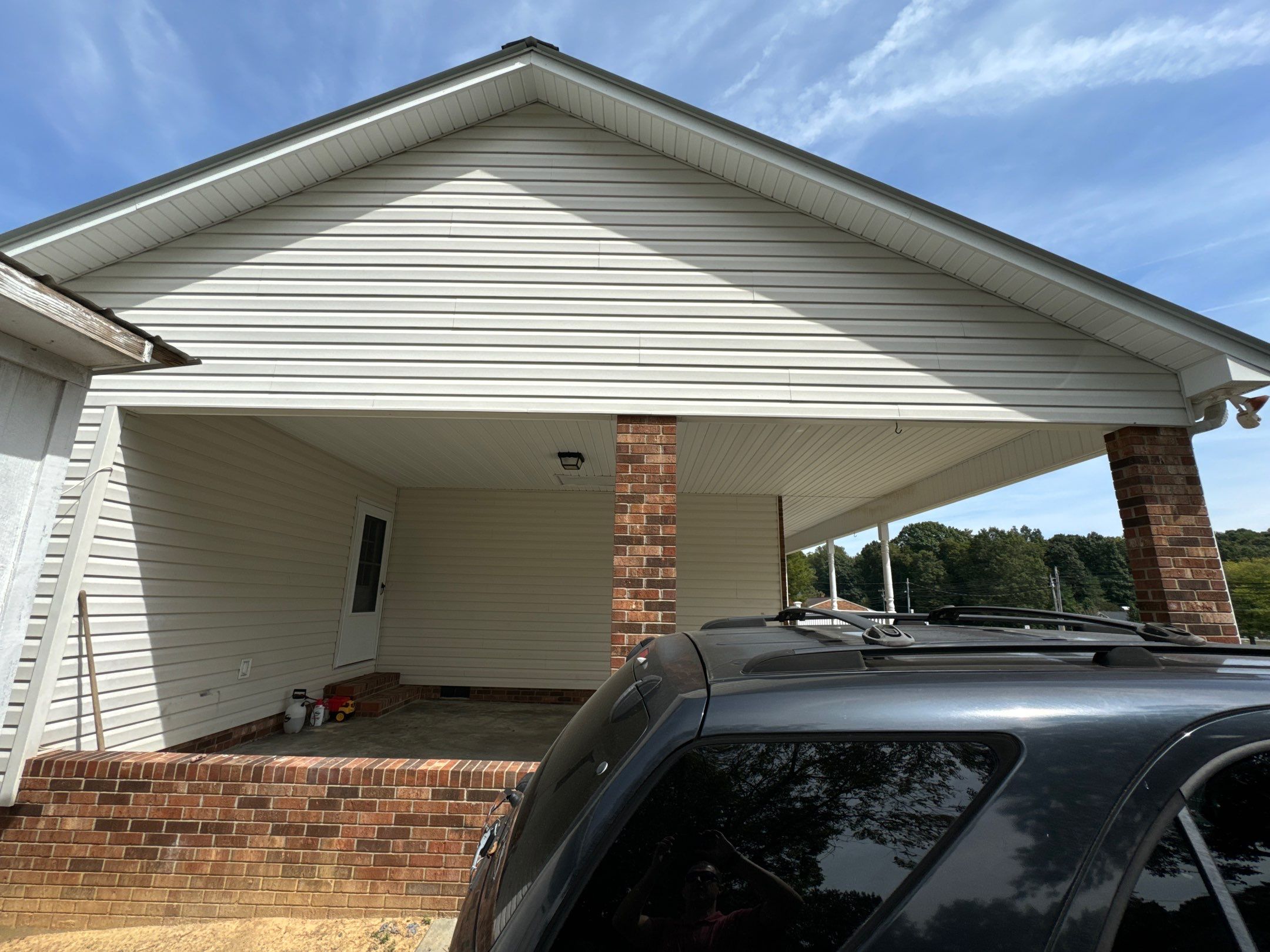 the service is cleaning the vinyl siding and brick columns of a house to remove dirt and stains