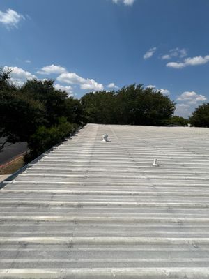 Corrugated metal roof surface with vents under blue sky