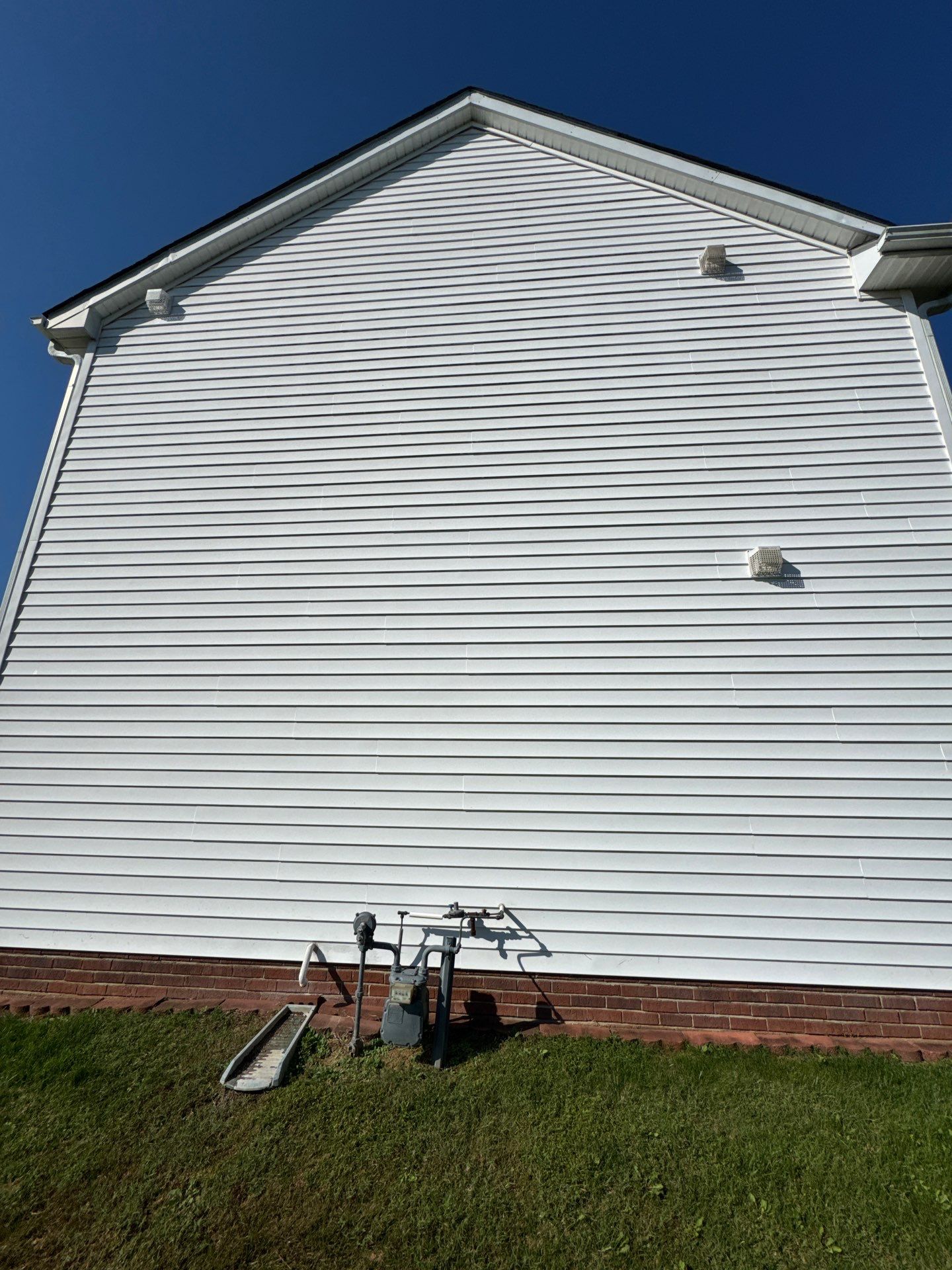 pressure washing service is being performed on a vinyl siding surface of a house for cleaning and maintenance