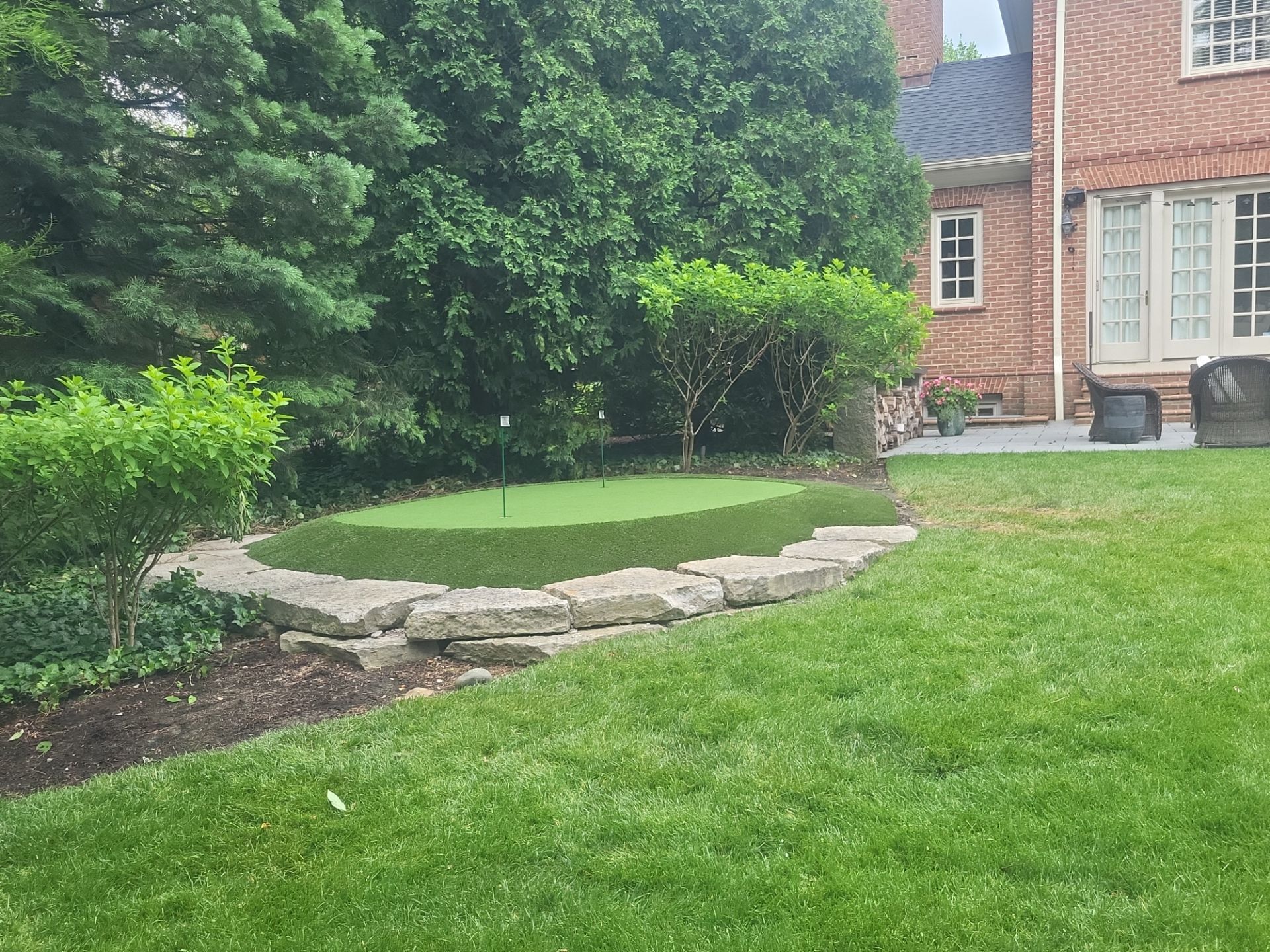 Small New Albany Synthetic Turf Putting Green with Natural Stone Border by Southwest Greens Midwest