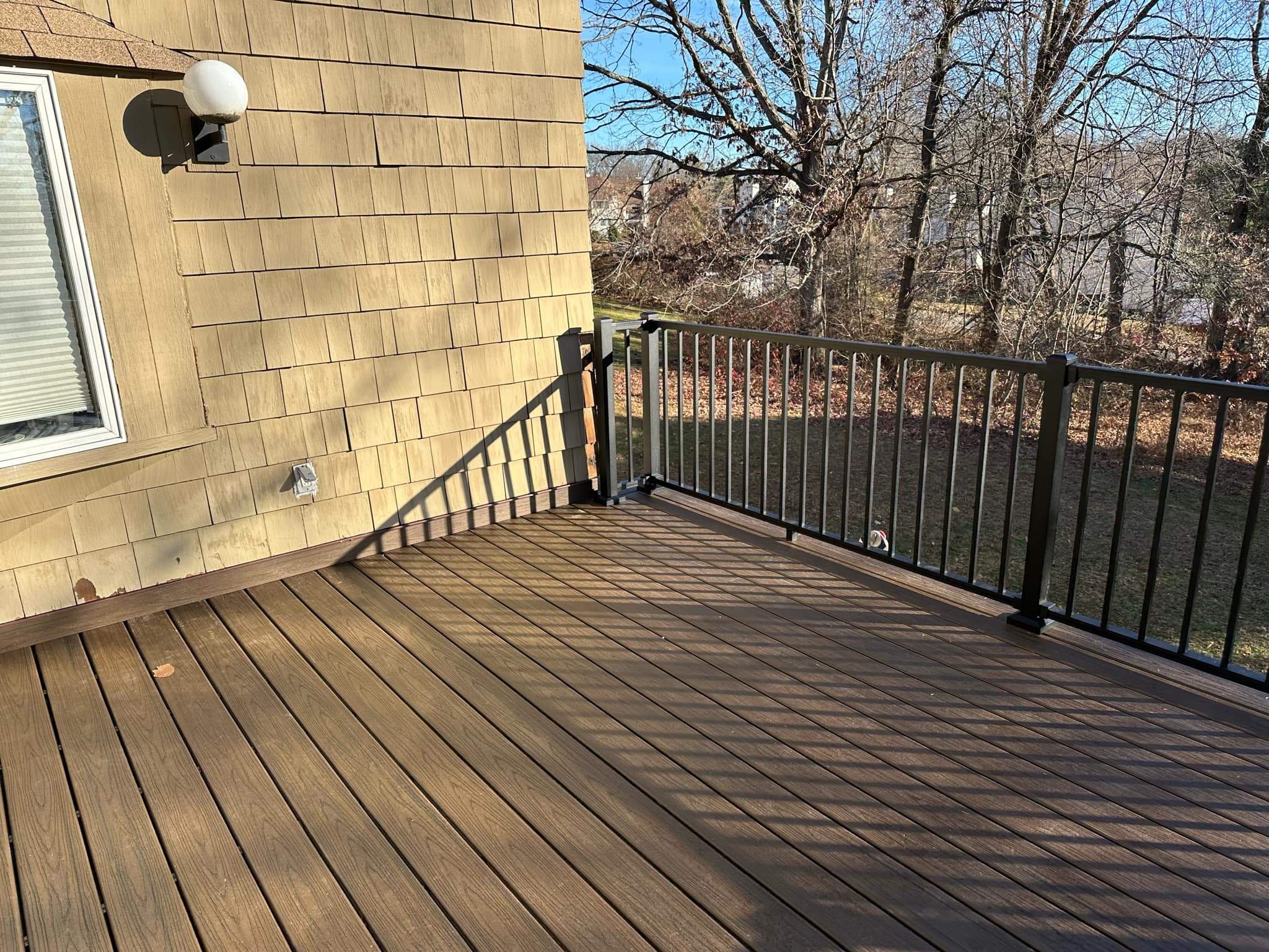 Replacement deck on top of flat roof, Trex Tropical Spiced rum boards and fascia, Trex signature aluminum railings in Black. by DiGiorgi Roofing and Siding Inc