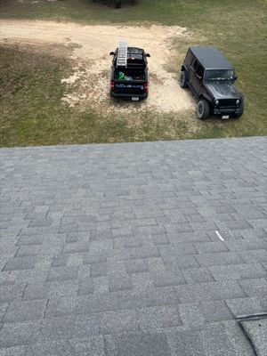 View of an asphalt shingle roof with two parked vehicles.