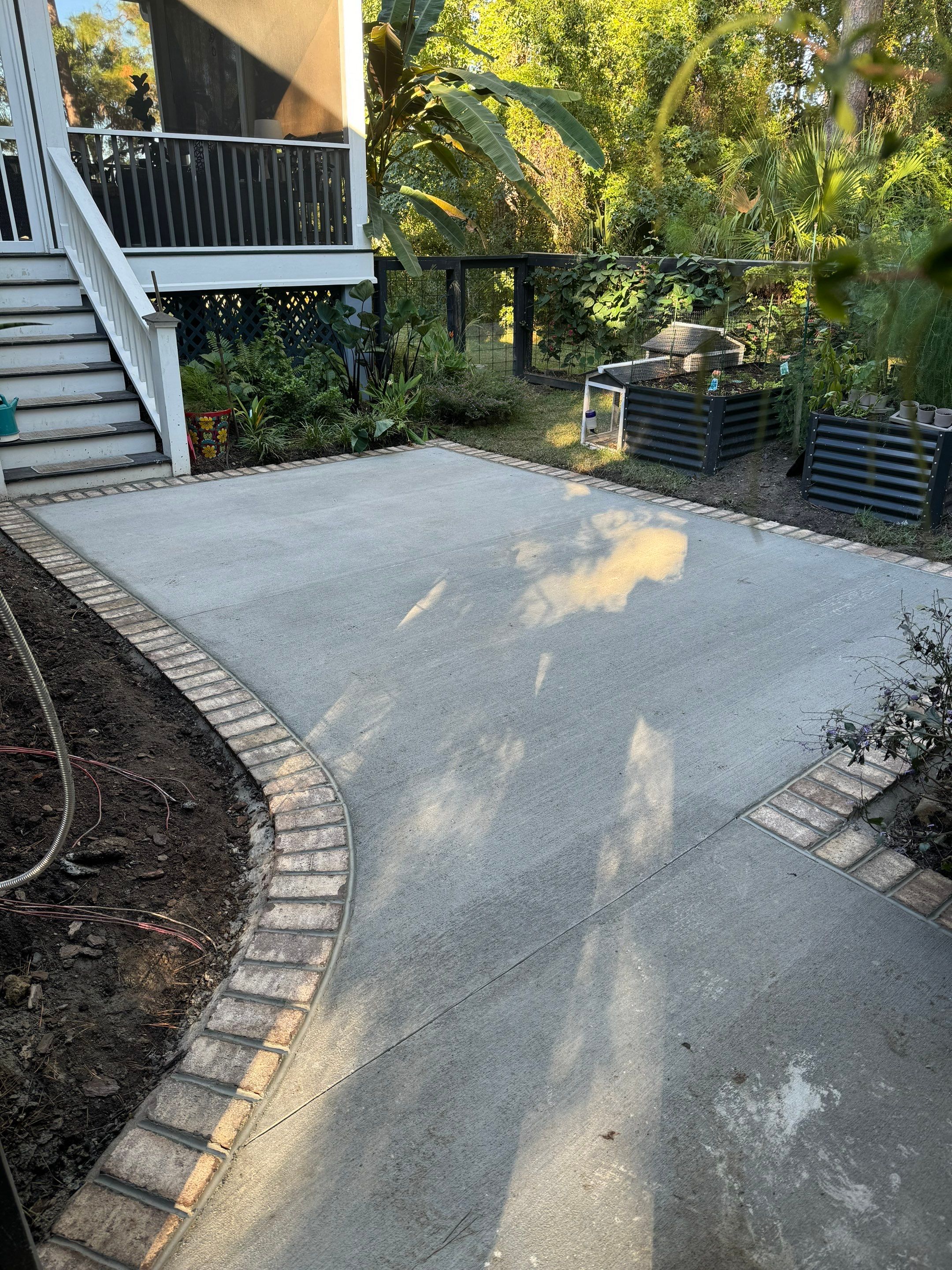 Concrete Driveway and Patio Installation With Decorative Brick Borders by Lowcountry Scapes, LLC