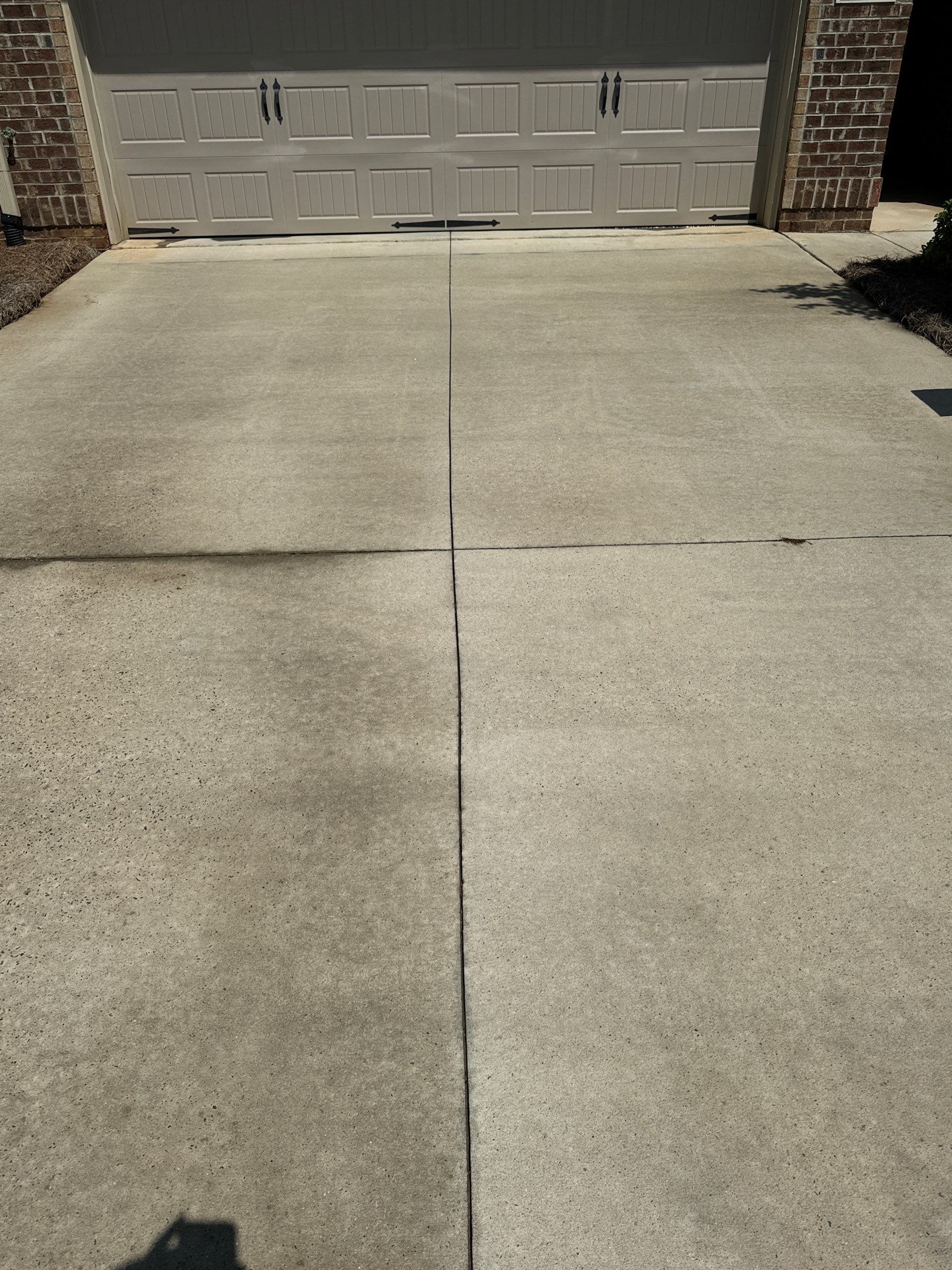 the image shows a driveway being cleaned with pressure washing revealing a clean and fresh concrete surface after treatment