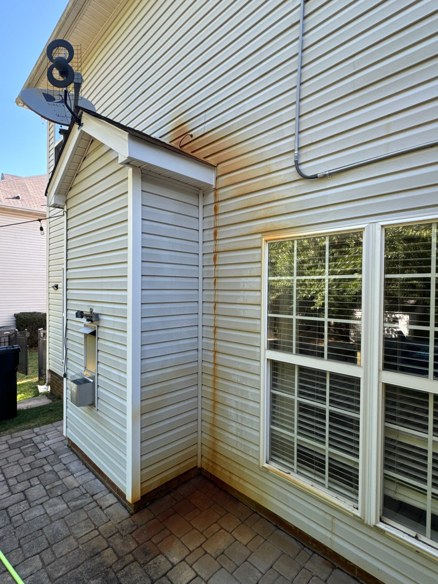 cleaning siding and pavers of a house with pressure washing removing visible dirt and stains