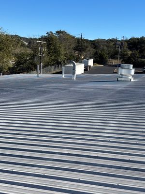 Metal roof with industrial exhaust fan and clear sky