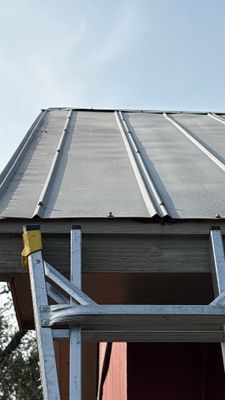 Worker on ladder installing metal roof panels