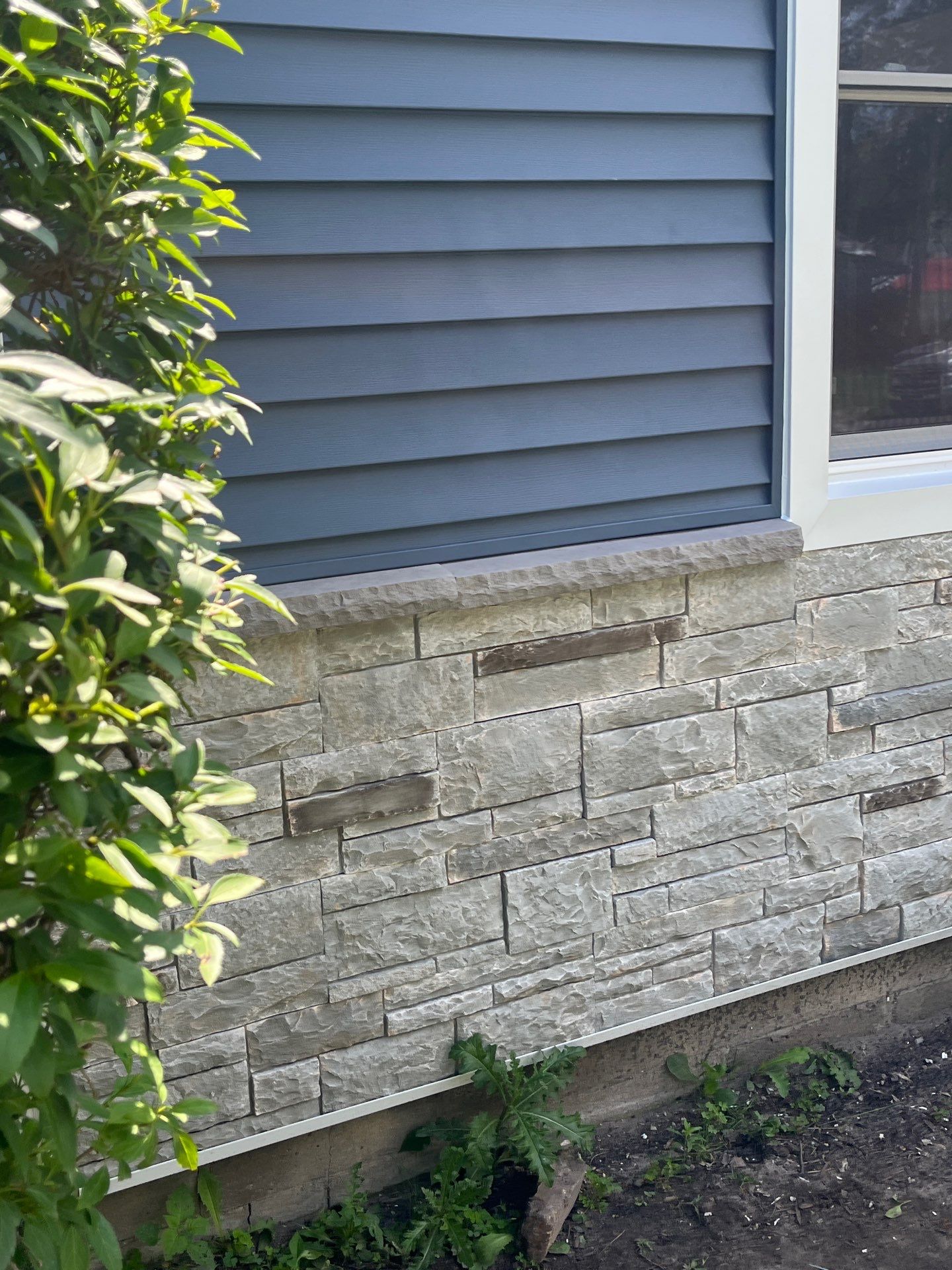 Blue Vinyl Siding and Versetta Stone Exterior Remodel in Bay City by Great Lakes Home Design LLC