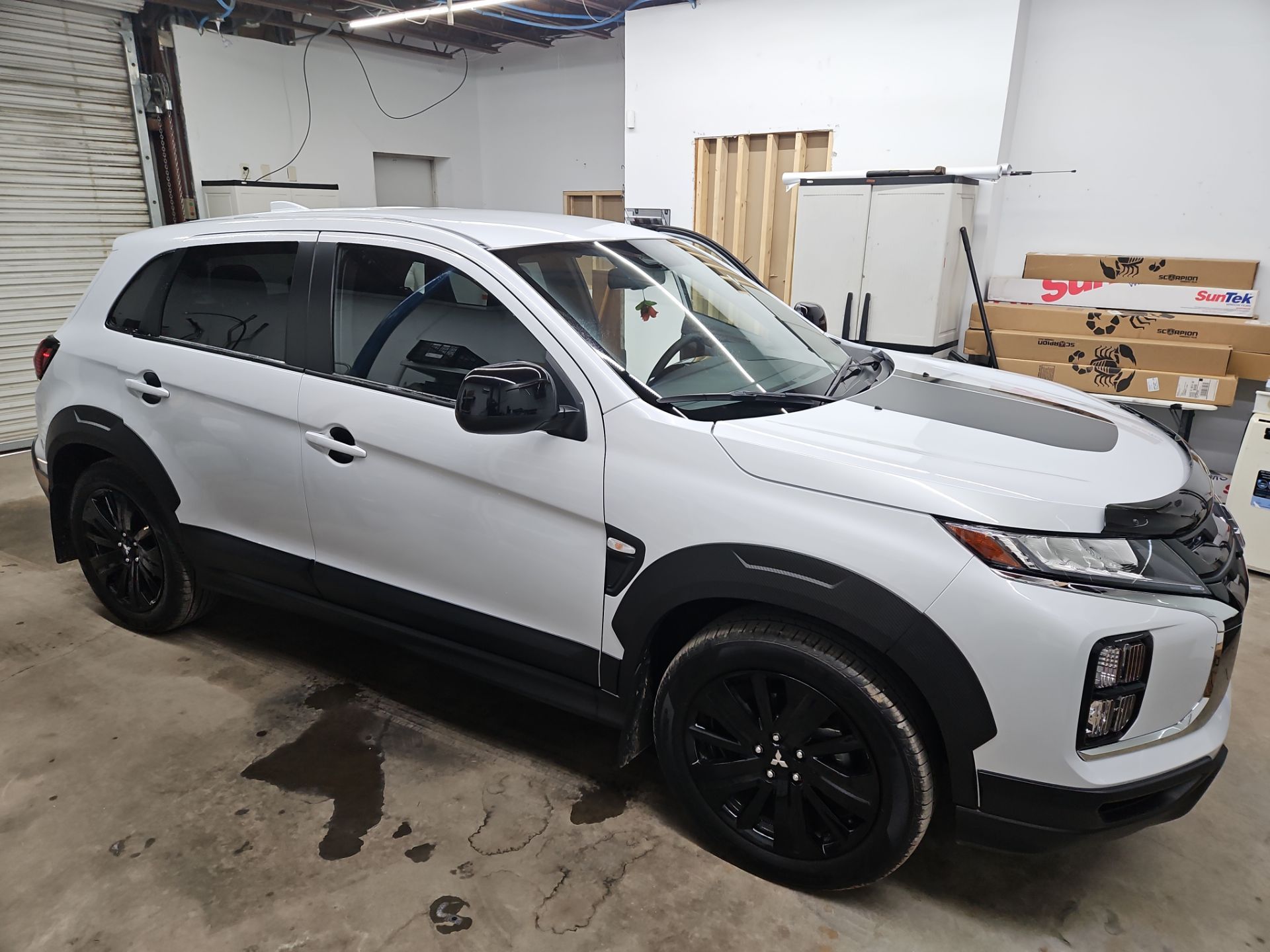 the service being done is window tinting on a white compact suv the windows are being covered with a specialized film to reduce glare and enhance privacy the car has a sleek look with blacked out wheels and accents the tinting will also help keep the interior cooler and protect against harmful uv rays the process involves cleaning the glass properly and applying the film meticulously to ensure a smooth finish and avoid bubbles or imperfections the overall result will give the vehicle a stylish appearance while providing functional benefits