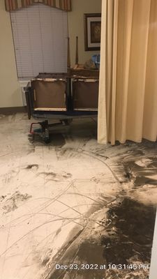 Tile floor with dark debris and tracking marks near chairs and privacy curtains inside a room.