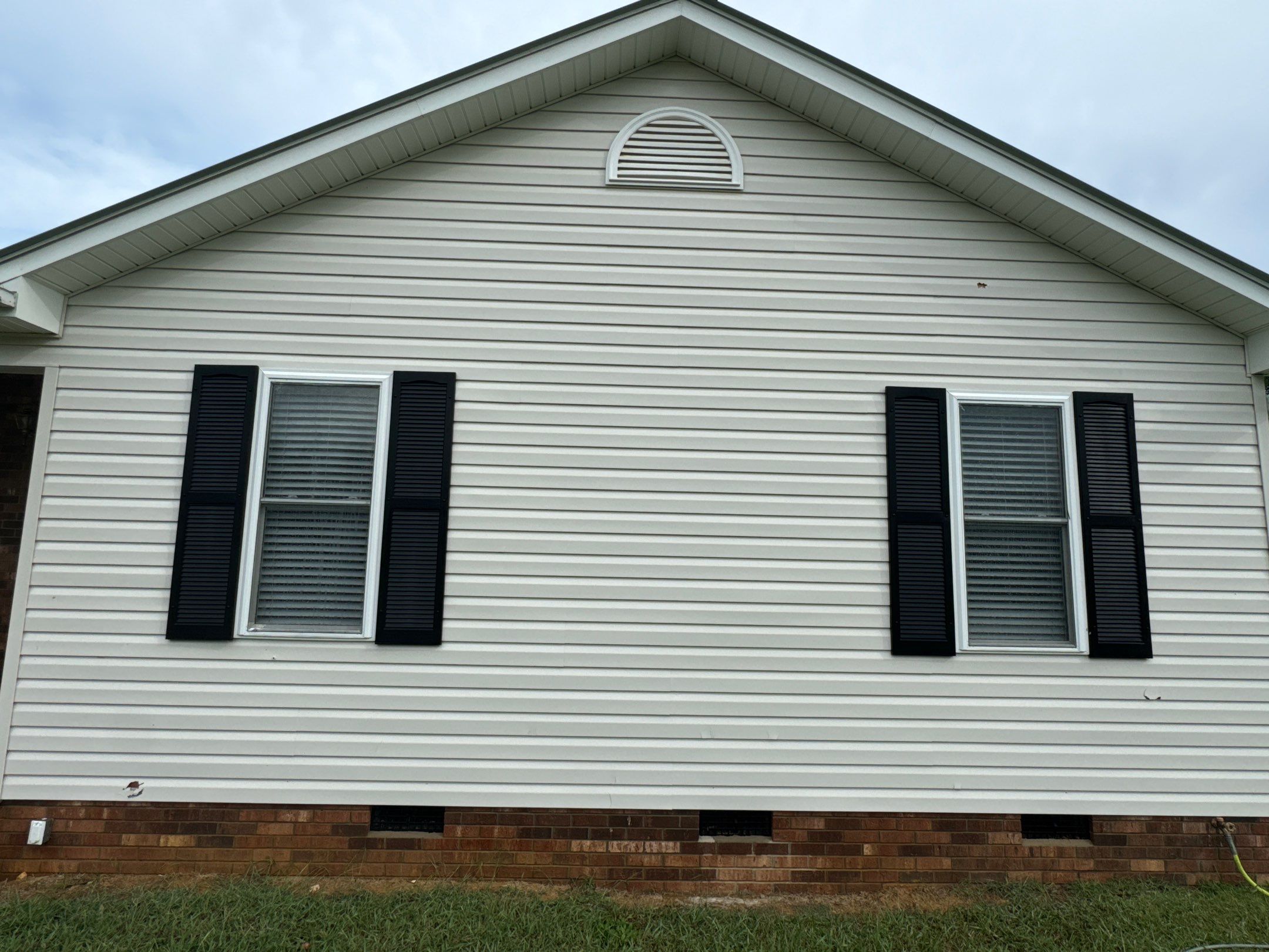 the service being done is cleaning the vinyl siding of the house to remove dirt and grime for improved appearance